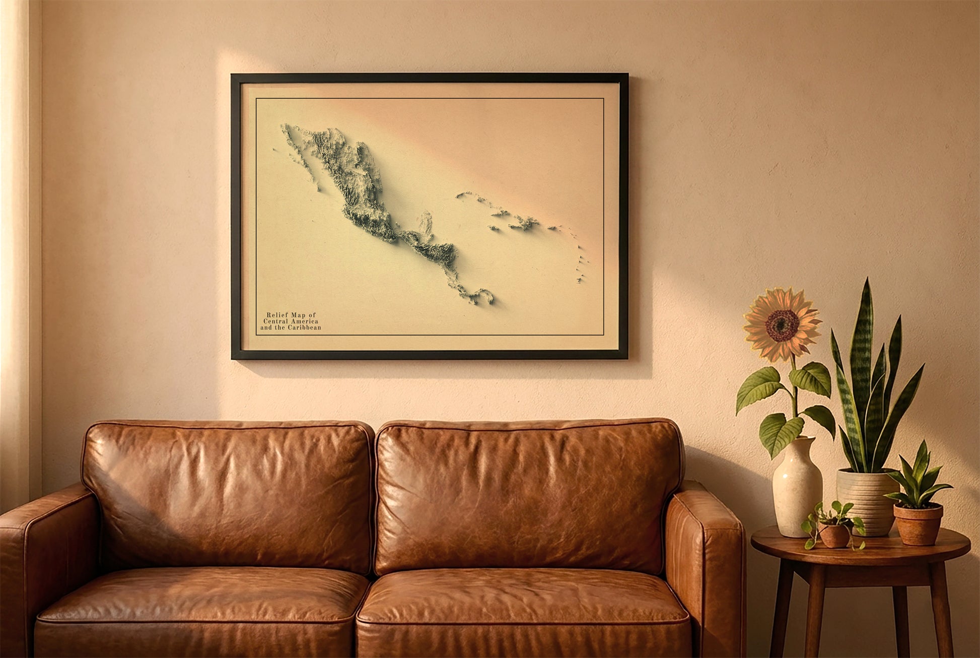 Central America and the Caribbean vintage relief map in a black frame above a brown leather sofa. Boho living room with warm sunlight, sunflower, and indoor plants on a wooden side table