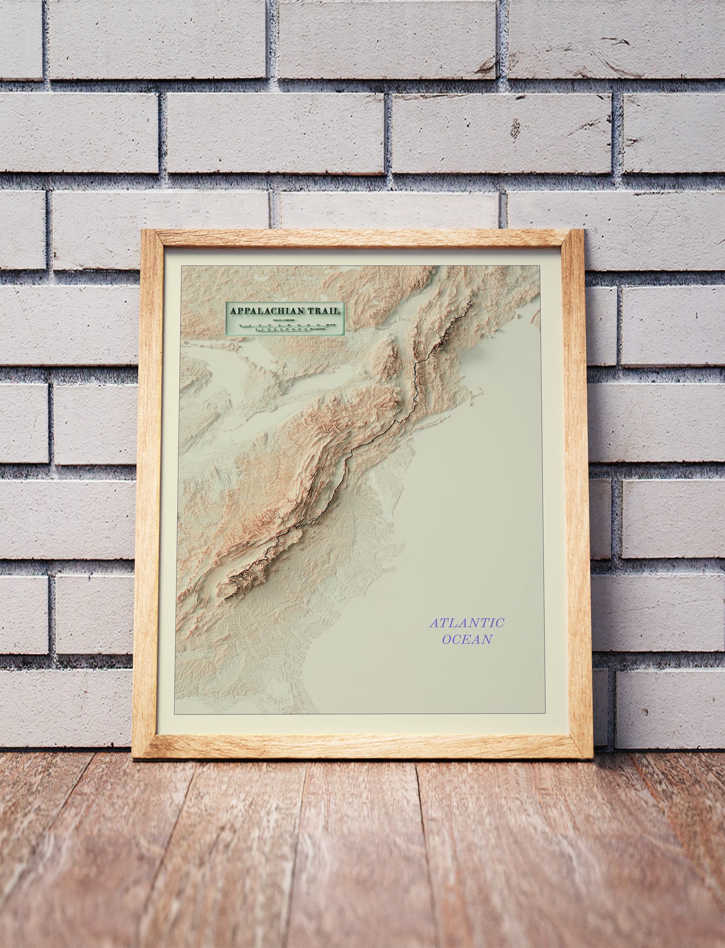 Vintage Appalachian Trail shaded relief map in a wooden frame. Realistic terrain art print for home decor, displayed against a brick wall