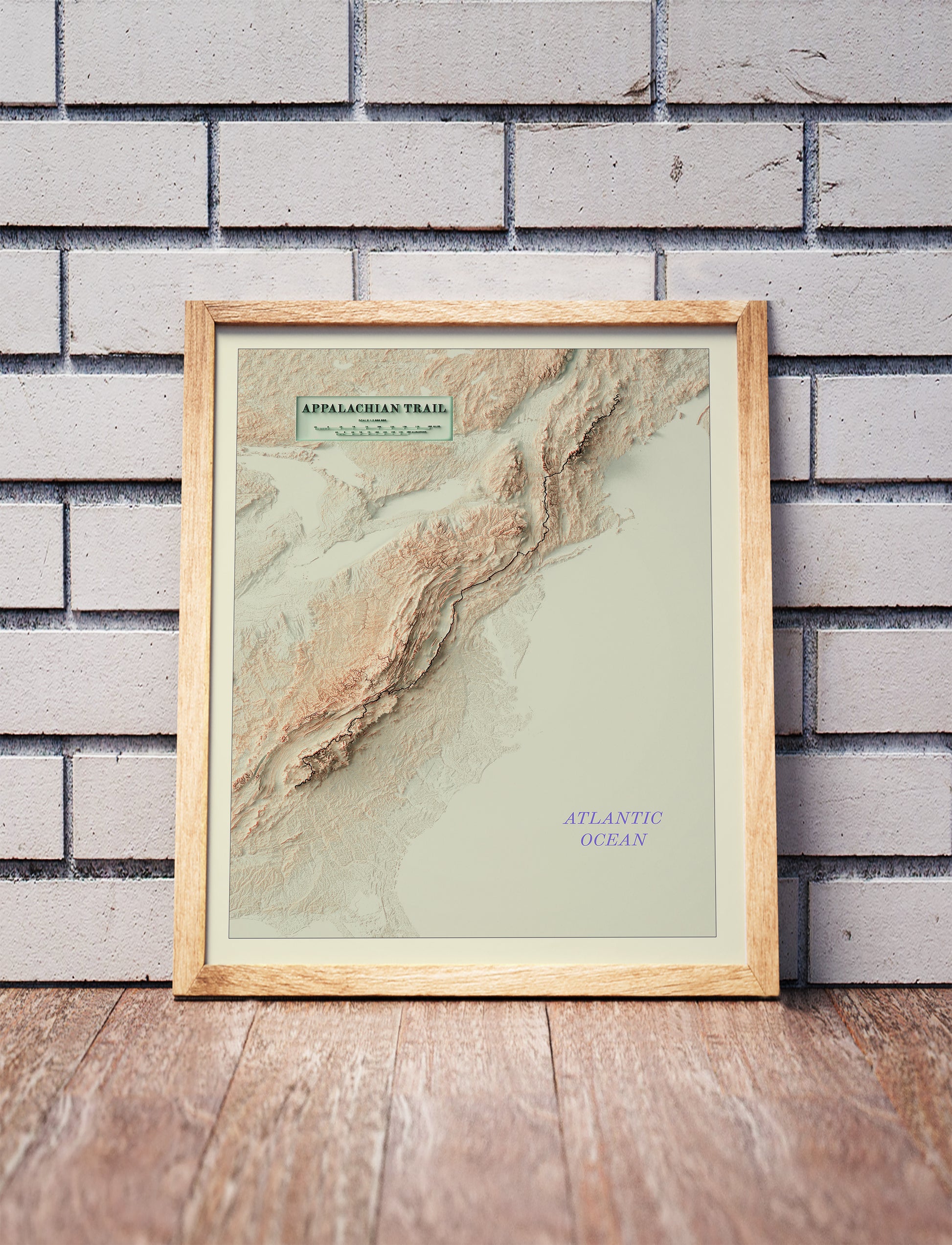 Vintage Appalachian Trail shaded relief map in a wooden frame. Realistic terrain art print for home decor, displayed against a brick wall