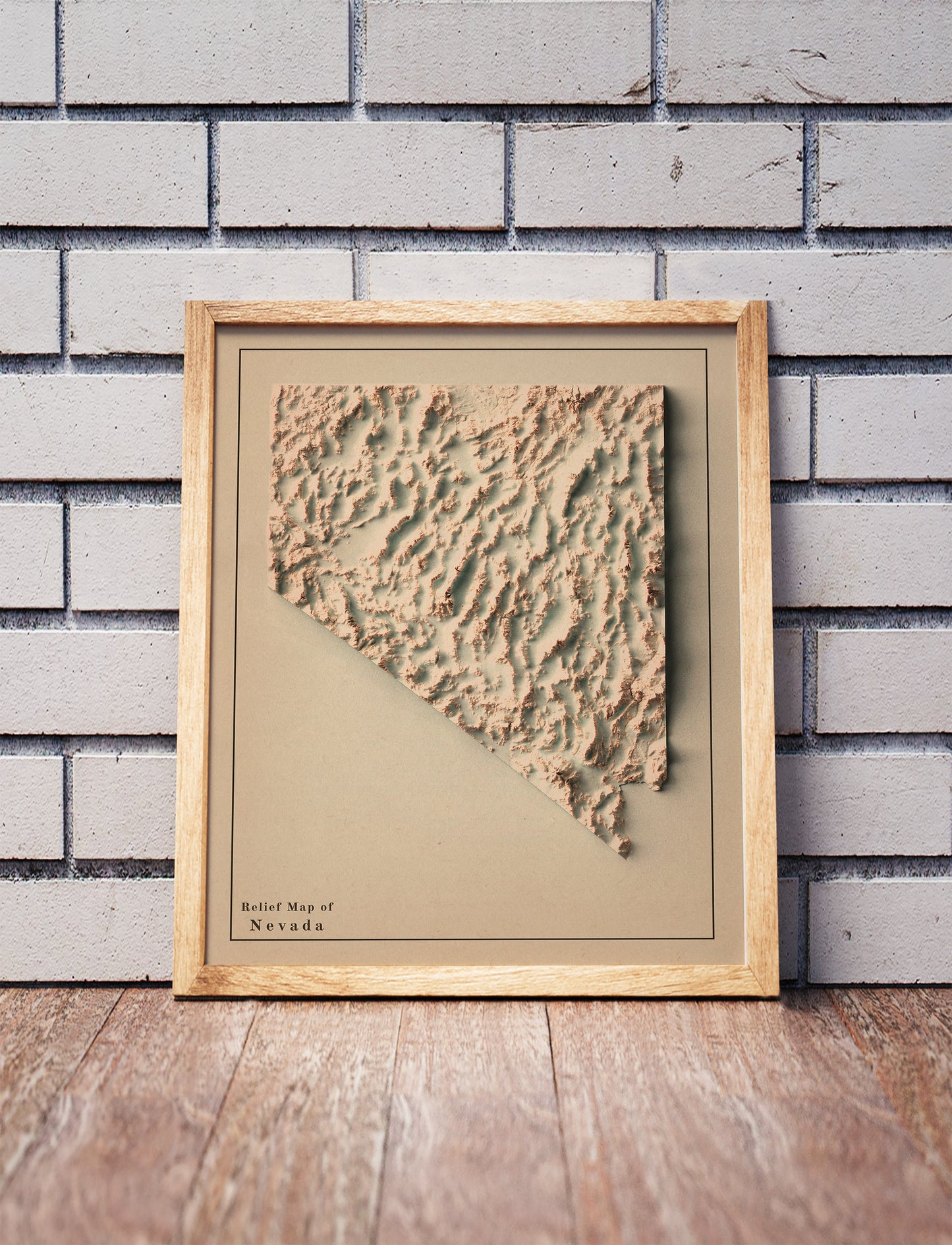 Vintage Nevada shaded relief map in a wooden frame. Realistic terrain art print for home decor, displayed against a brick wall