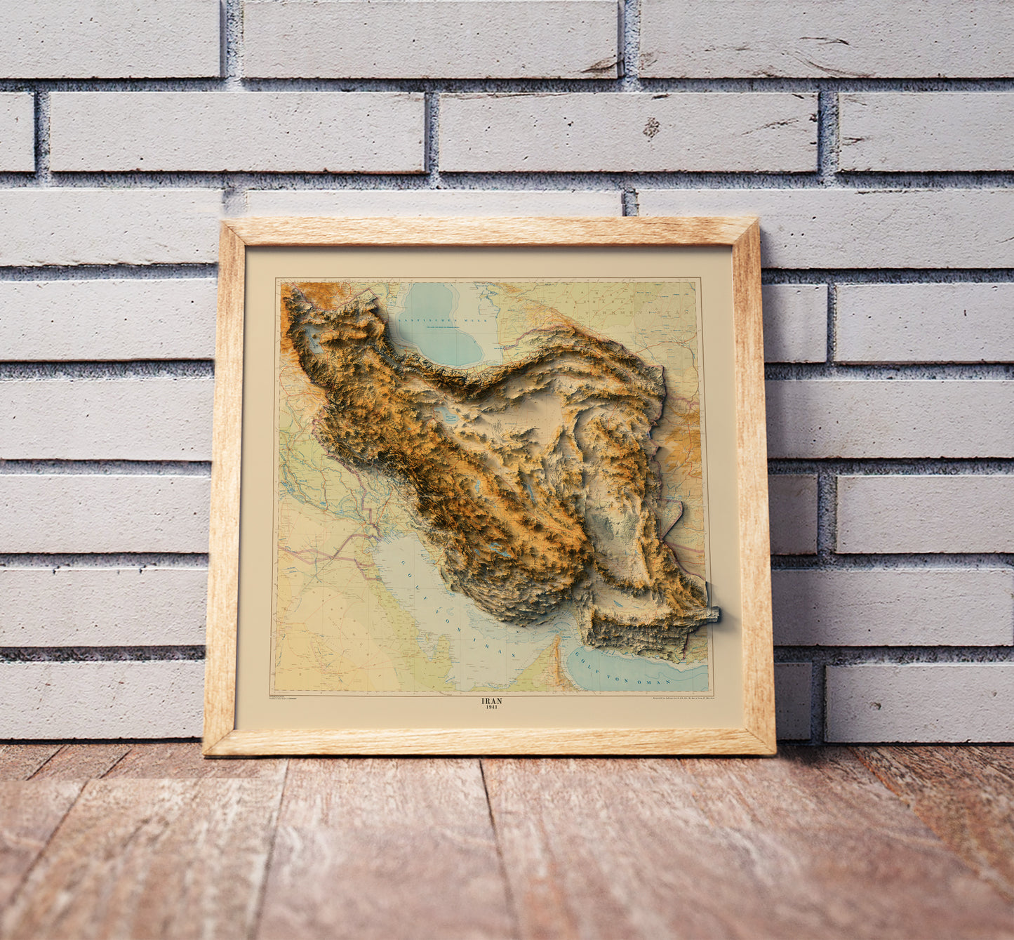 Vintage Iran shaded relief map in a wooden frame. Realistic terrain art print for home decor, displayed against a brick wall