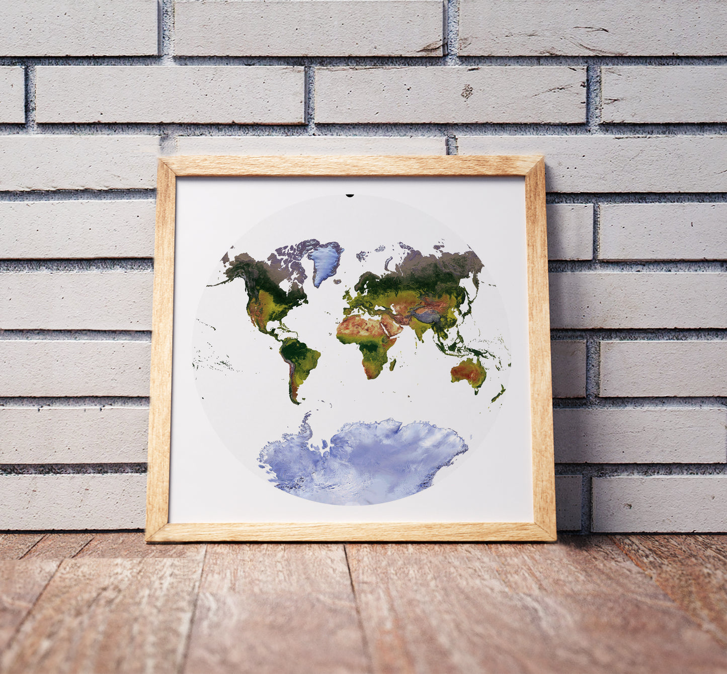 Van der Grinten projection shaded relief world map in a wooden frame. Realistic terrain art print for home decor, displayed against a brick wall