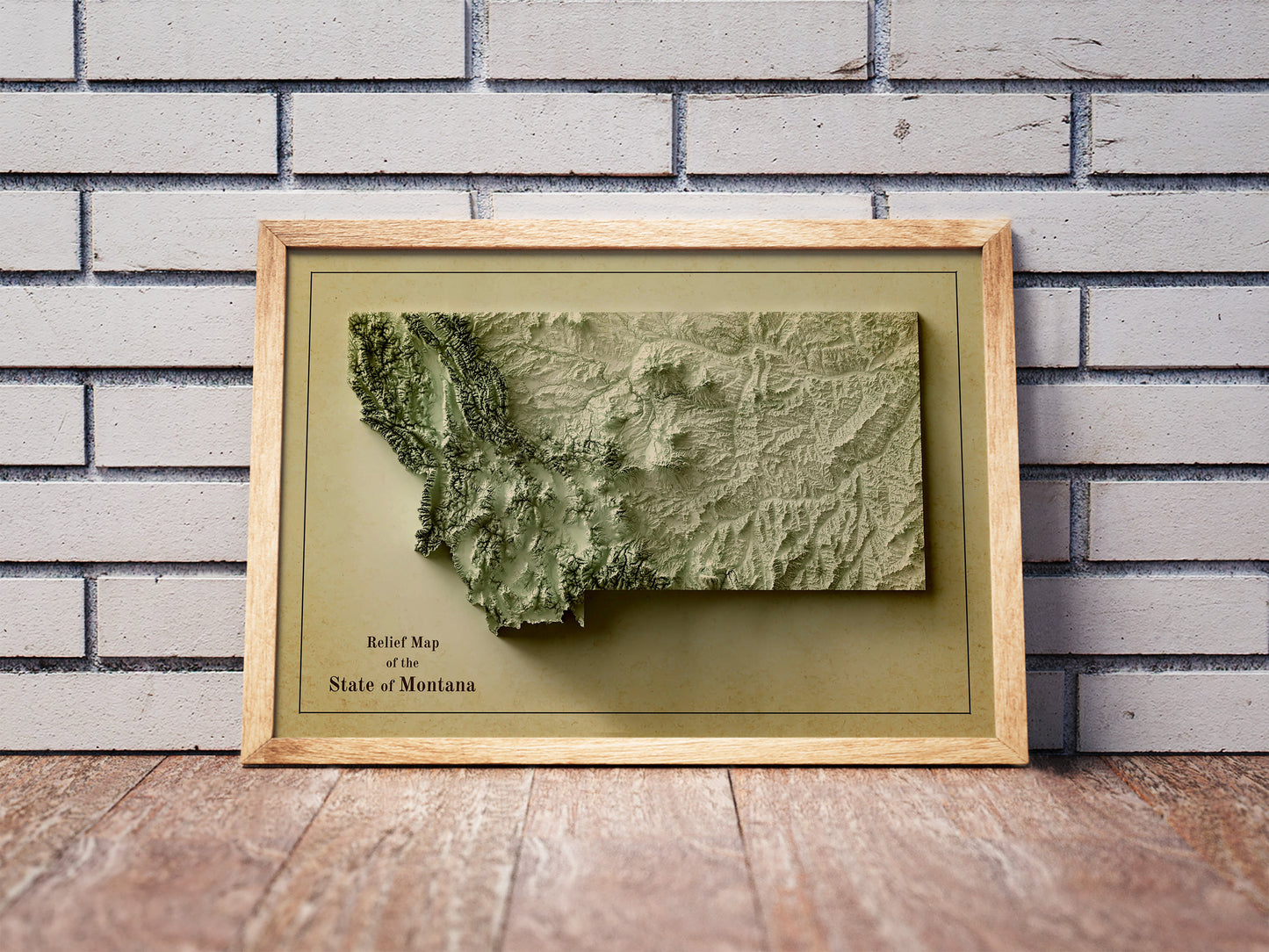 Vintage Montana shaded relief map in a wooden frame. Realistic terrain art print for home decor, displayed against a brick wall