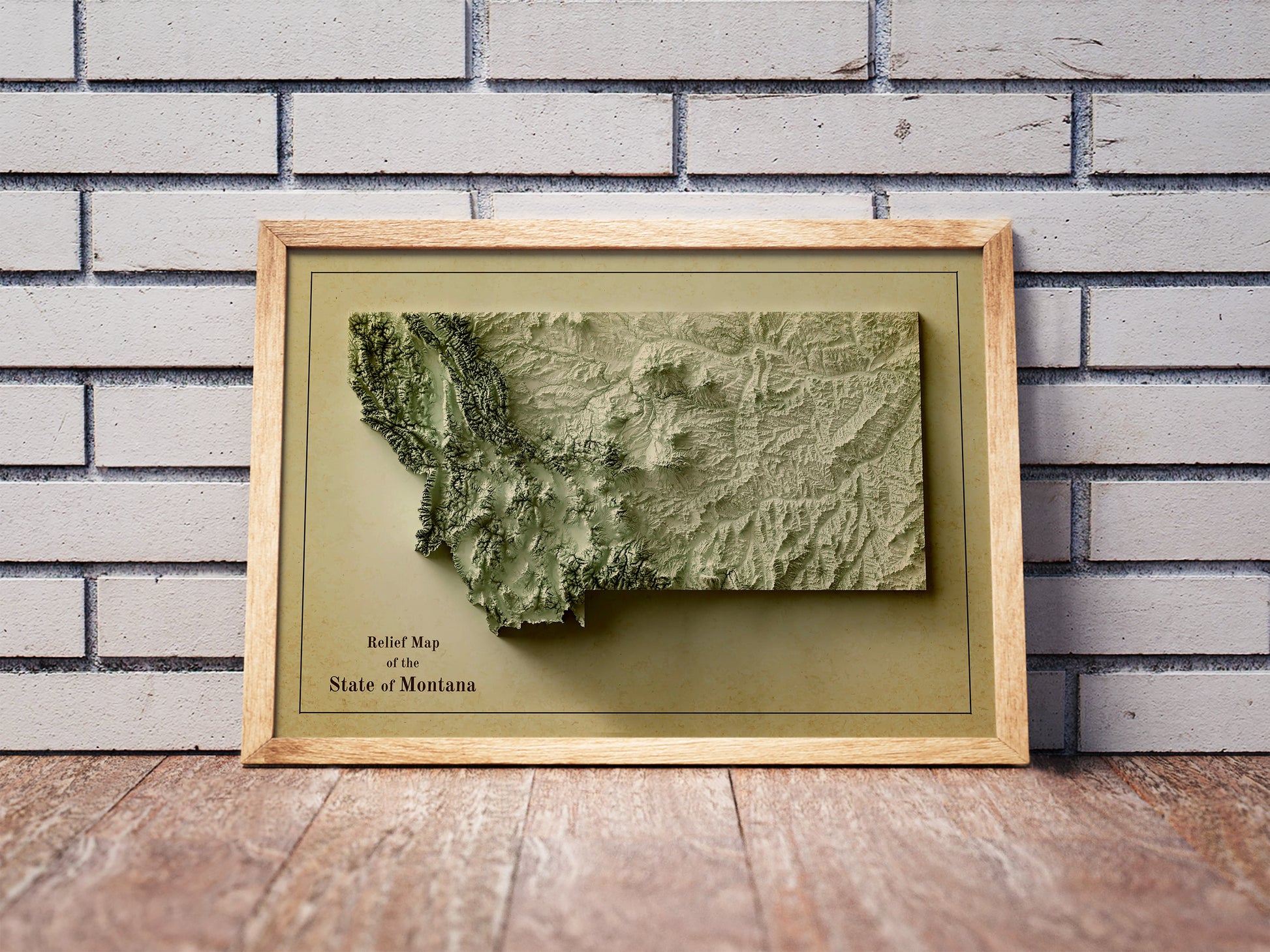 Vintage Montana shaded relief map in a wooden frame. Realistic terrain art print for home decor, displayed against a brick wall