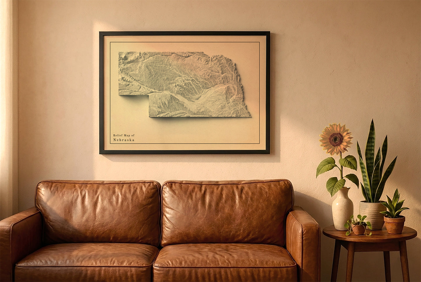 Nebraska vintage relief map in a black frame above a brown leather sofa. Boho living room with warm sunlight, sunflower, and indoor plants on a wooden side table
