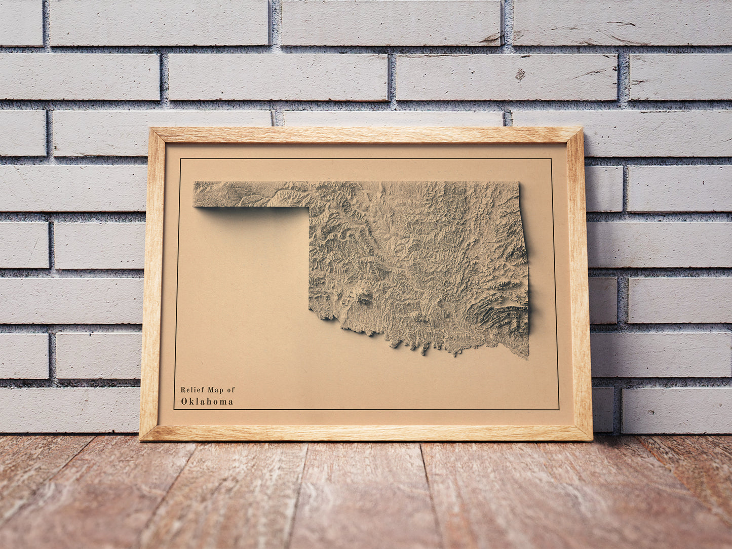 Vintage Oklahoma shaded relief map in a wooden frame. Realistic terrain art print for home decor, displayed against a brick wall