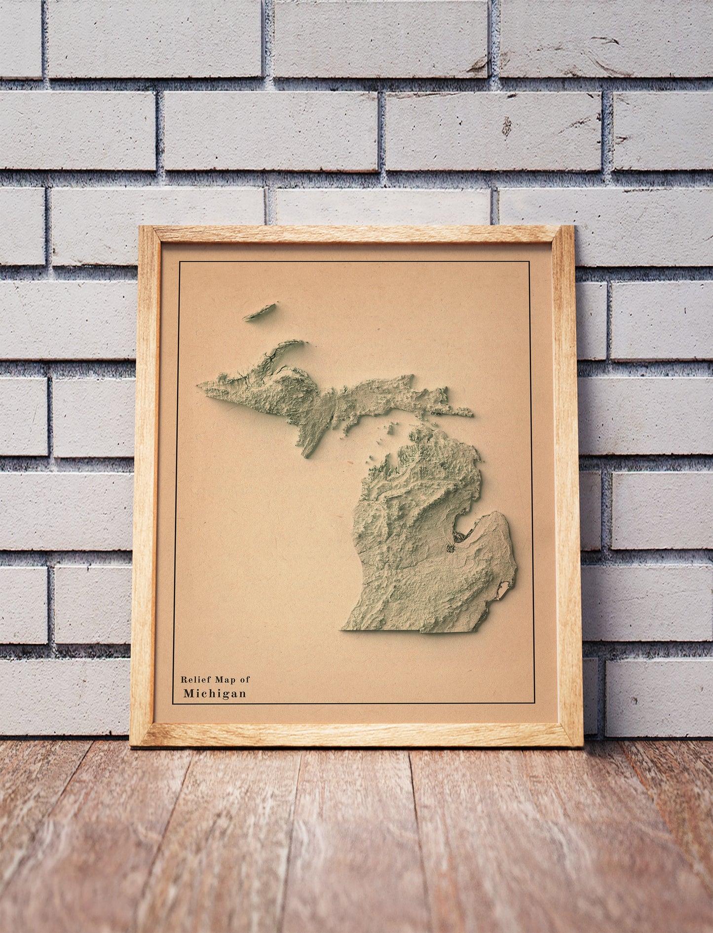Vintage Michigan shaded relief map in a wooden frame. Realistic terrain art print for home decor, displayed against a brick wall