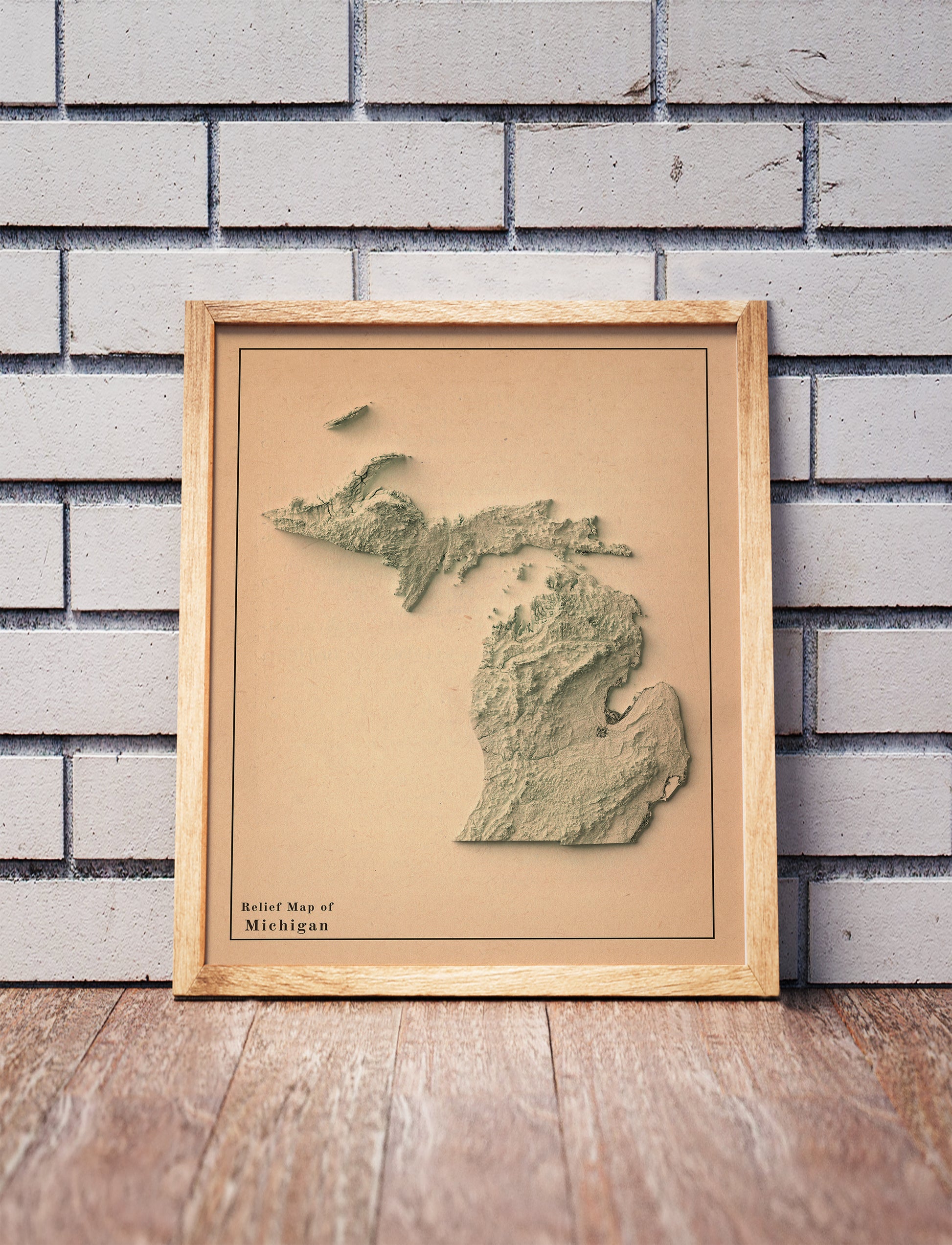 Vintage Michigan shaded relief map in a wooden frame. Realistic terrain art print for home decor, displayed against a brick wall