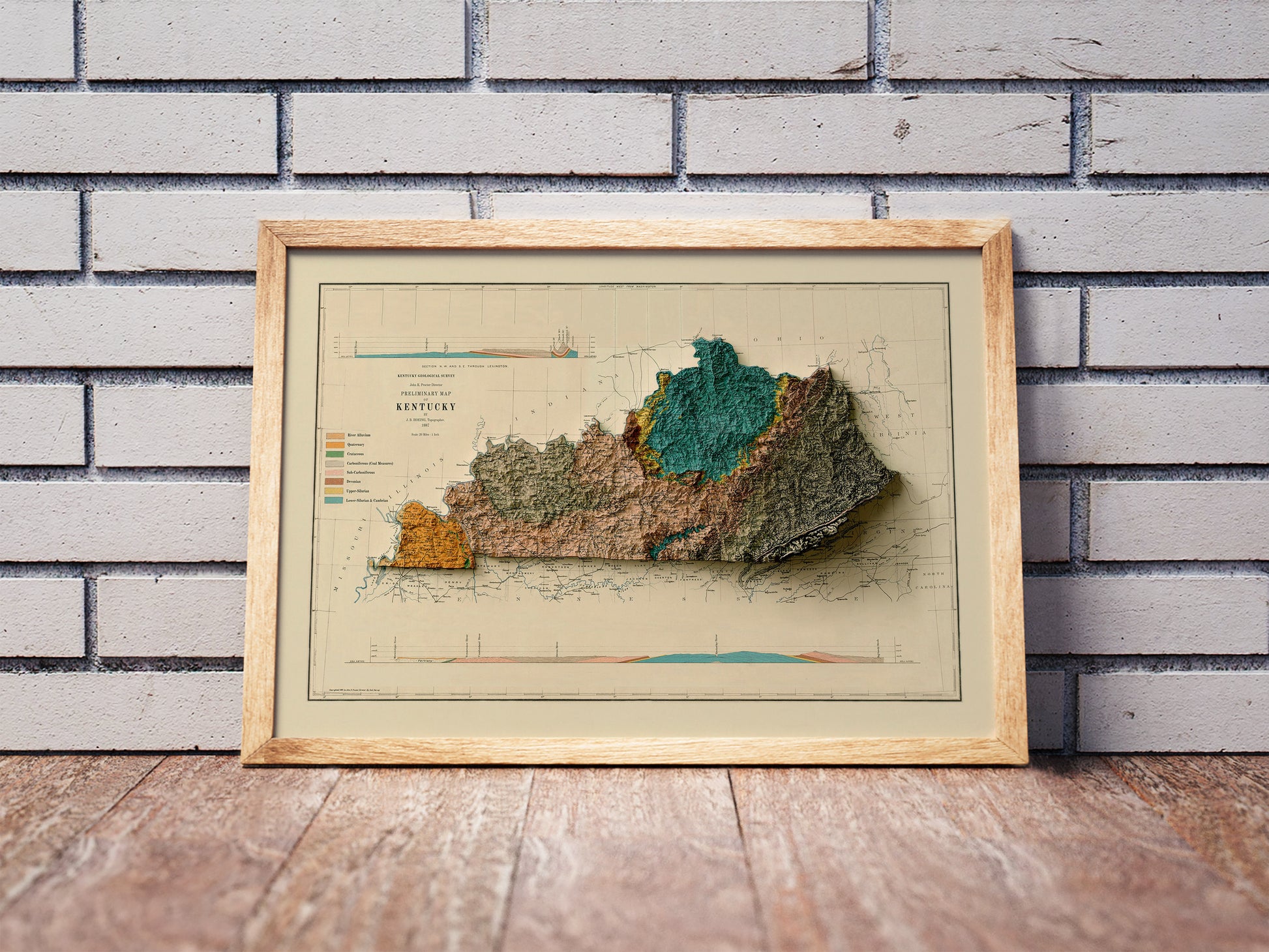 Vintage Kentucky shaded relief map in a wooden frame. Realistic terrain art print for home decor, displayed against a brick wall