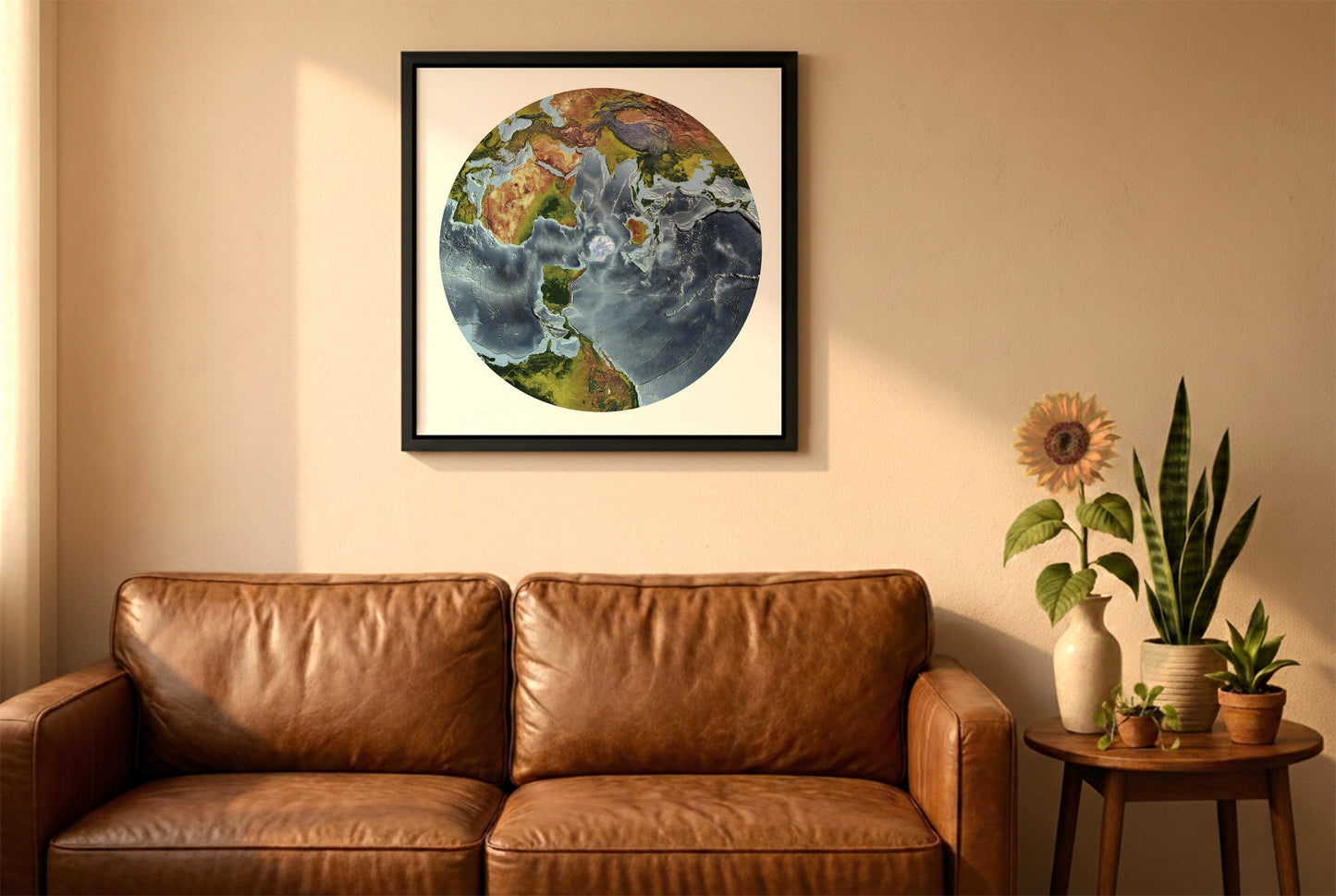 World relief map in australian antarctic polar projection in a black frame above a brown leather sofa. Boho living room with warm sunlight, sunflower, and indoor plants on a wooden side table