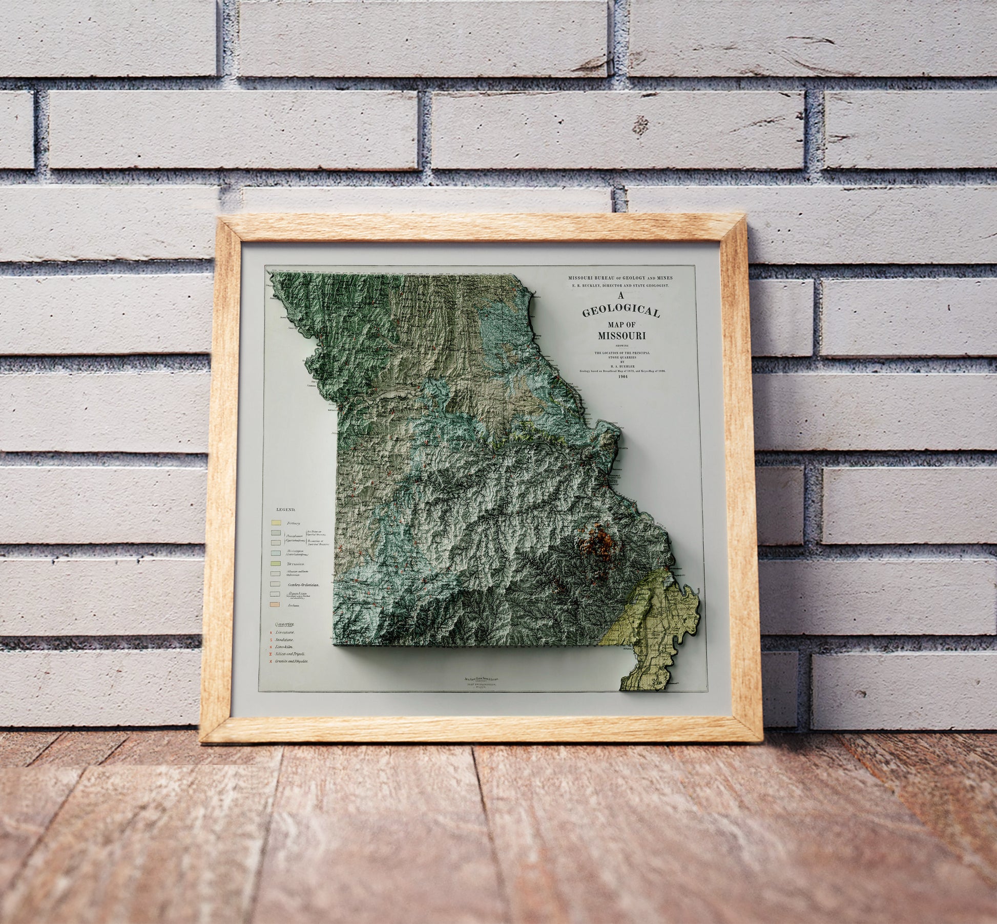 Vintage Missouri shaded relief map in a wooden frame. Realistic terrain art print for home decor, displayed against a brick wall