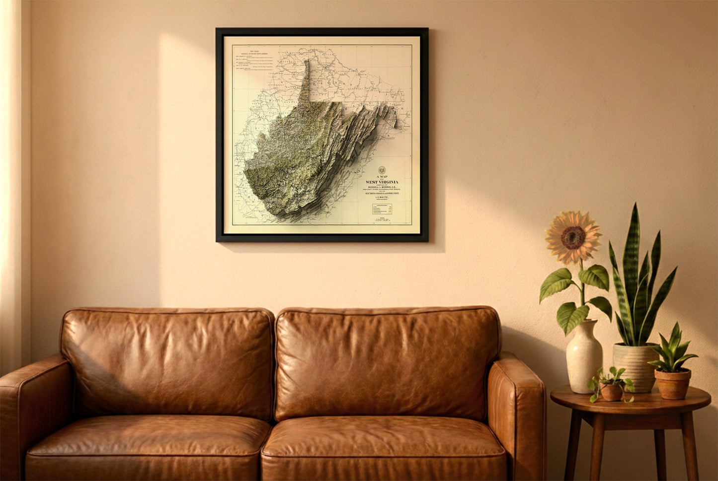 West Virginia vintage relief map in a black frame above a brown leather sofa. Boho living room with warm sunlight, sunflower, and indoor plants on a wooden side table