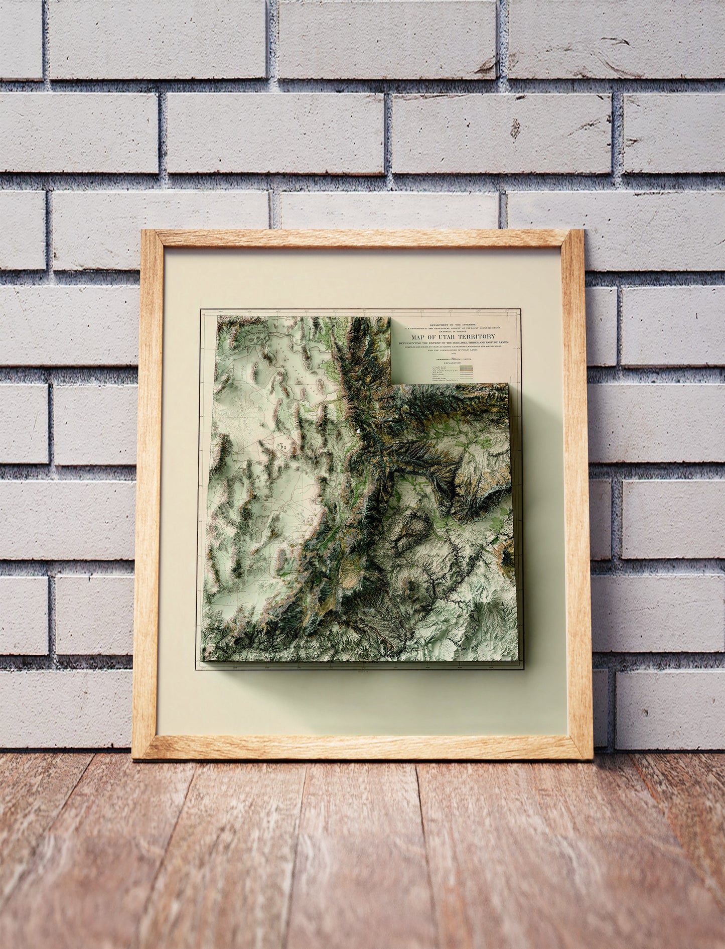 Vintage utah shaded relief map in a wooden frame. Realistic terrain art print for home decor, displayed against a brick wall