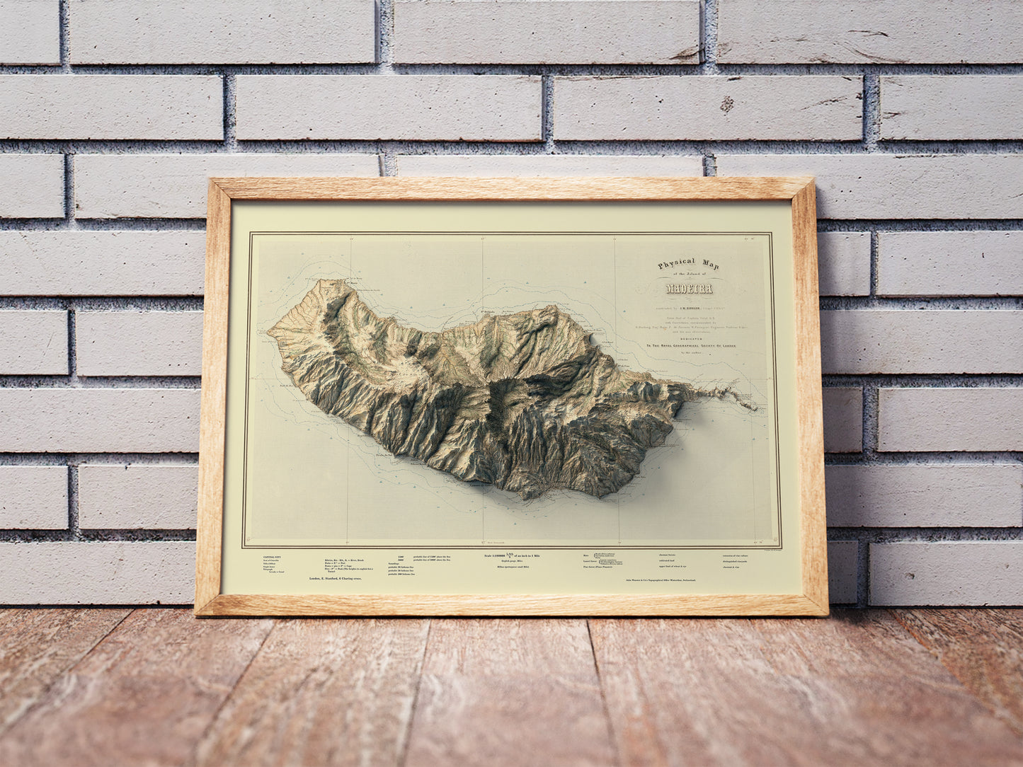 Vintage Madeira Island, Portugal, shaded relief map in a wooden frame. Realistic terrain art print for home decor, displayed against a brick wall