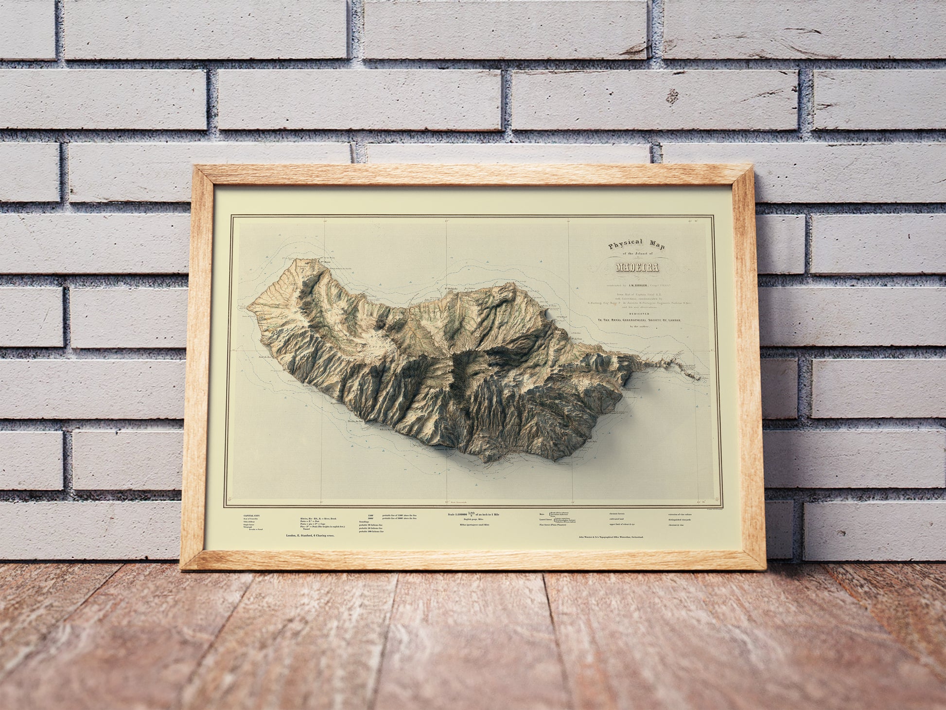 Vintage Madeira Island, Portugal, shaded relief map in a wooden frame. Realistic terrain art print for home decor, displayed against a brick wall