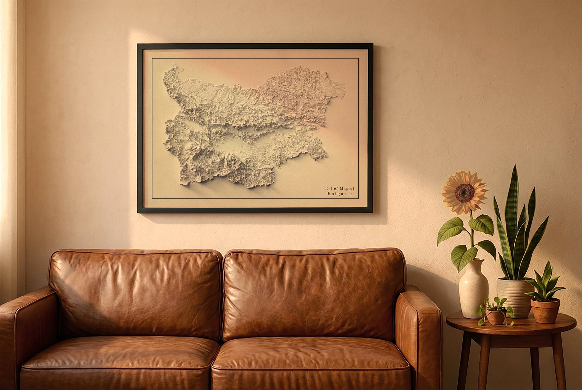 Bulgaria vintage relief map in a black frame above a brown leather sofa. Boho living room with warm sunlight, sunflower, and indoor plants on a wooden side table
