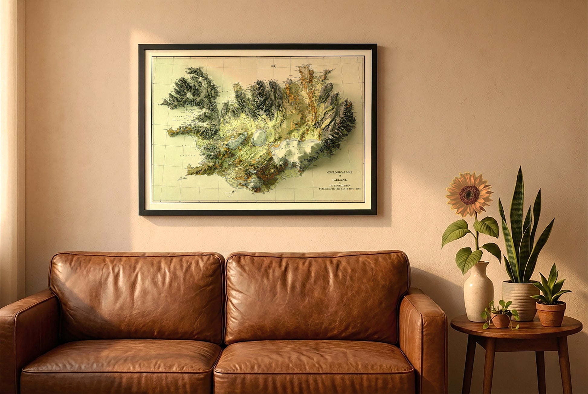 Iceland vintage relief map in a black frame above a brown leather sofa. Boho living room with warm sunlight, sunflower, and indoor plants on a wooden side table