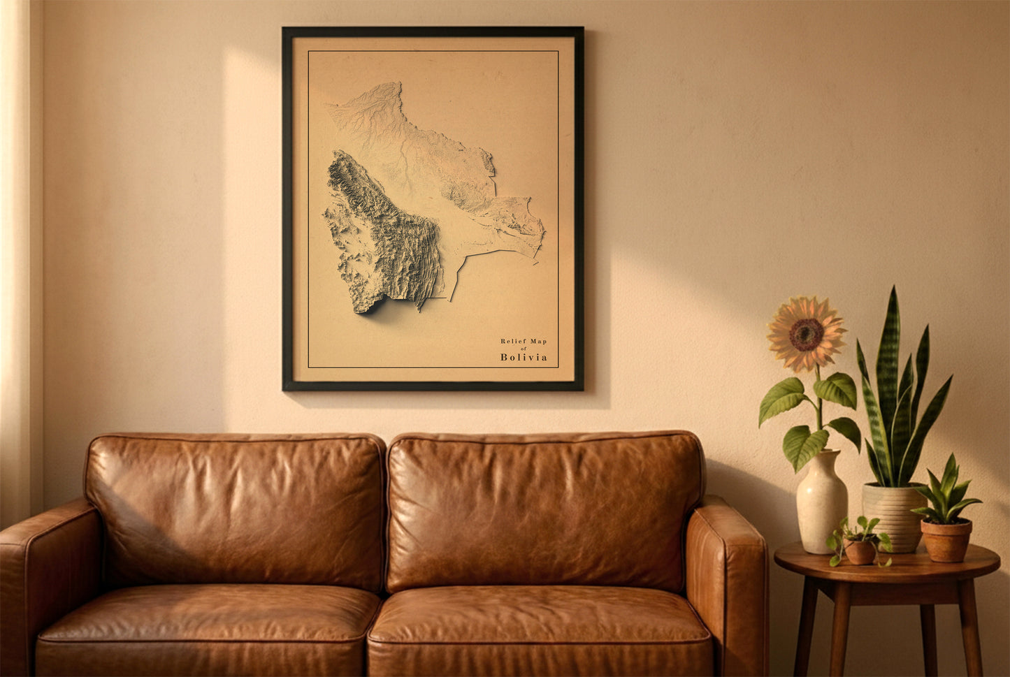 Bolivia vintage relief map in a black frame above a brown leather sofa. Boho living room with warm sunlight, sunflower, and indoor plants on a wooden side table