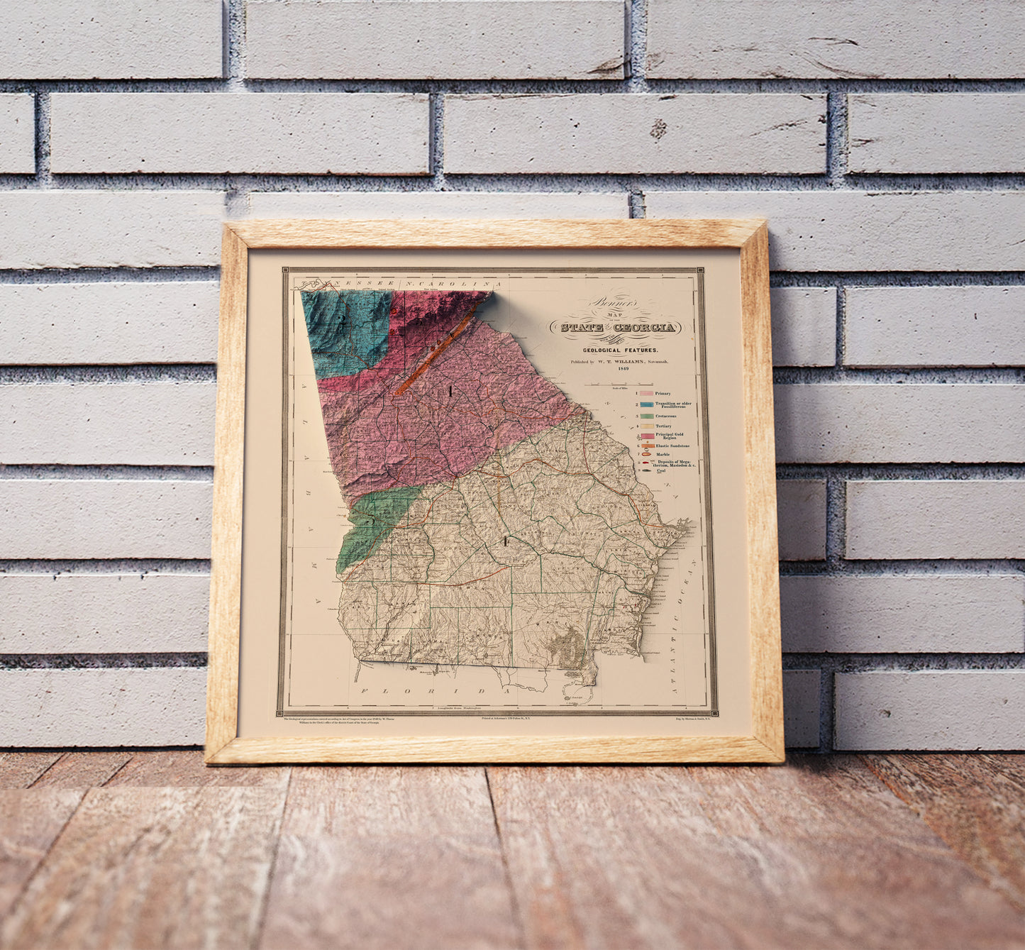 Vintage Georgia shaded relief map in a wooden frame. Realistic terrain art print for home decor, displayed against a brick wall