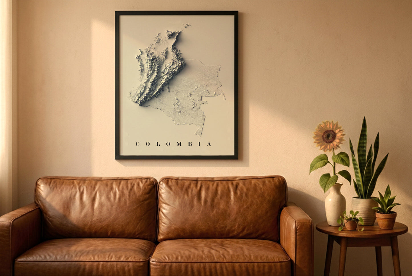 Colombia relief map in a black frame above a brown leather sofa. Boho living room with warm sunlight, sunflower, and indoor plants on a wooden side table
