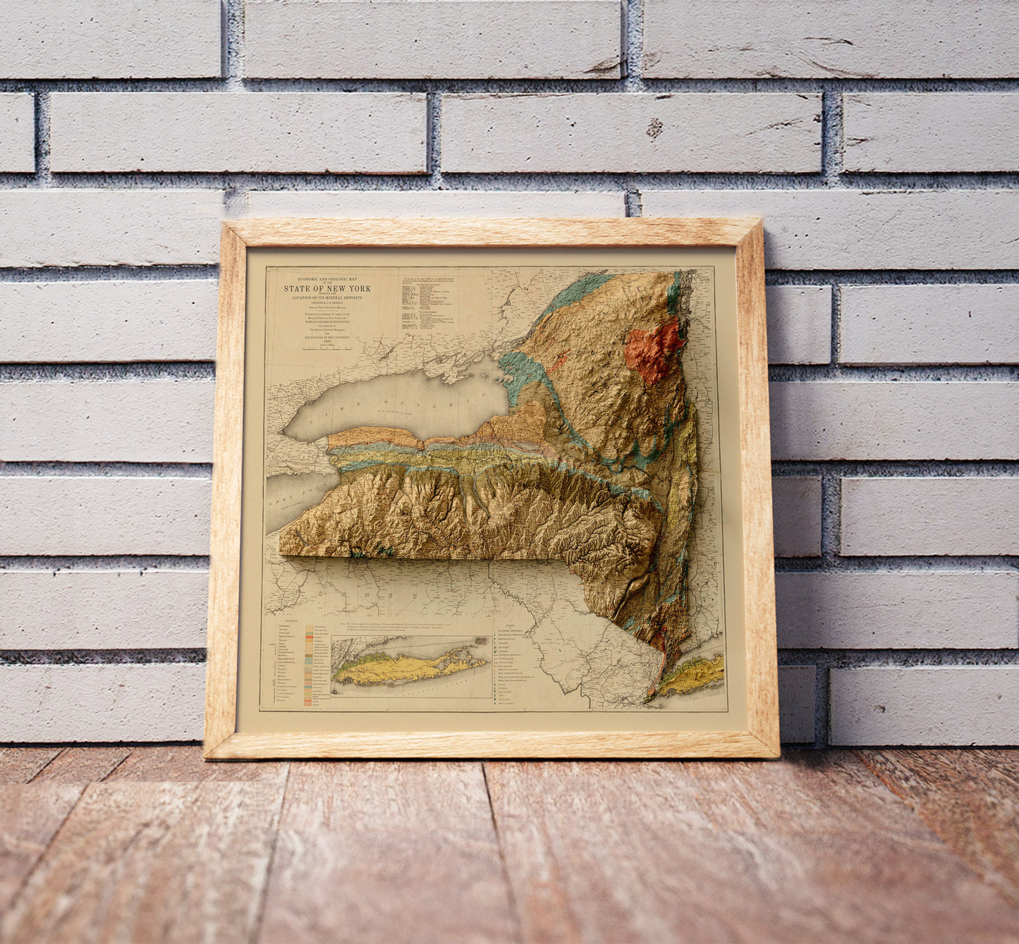 Vintage New York state shaded relief map in a wooden frame. Realistic terrain art print for home decor, displayed against a brick wall