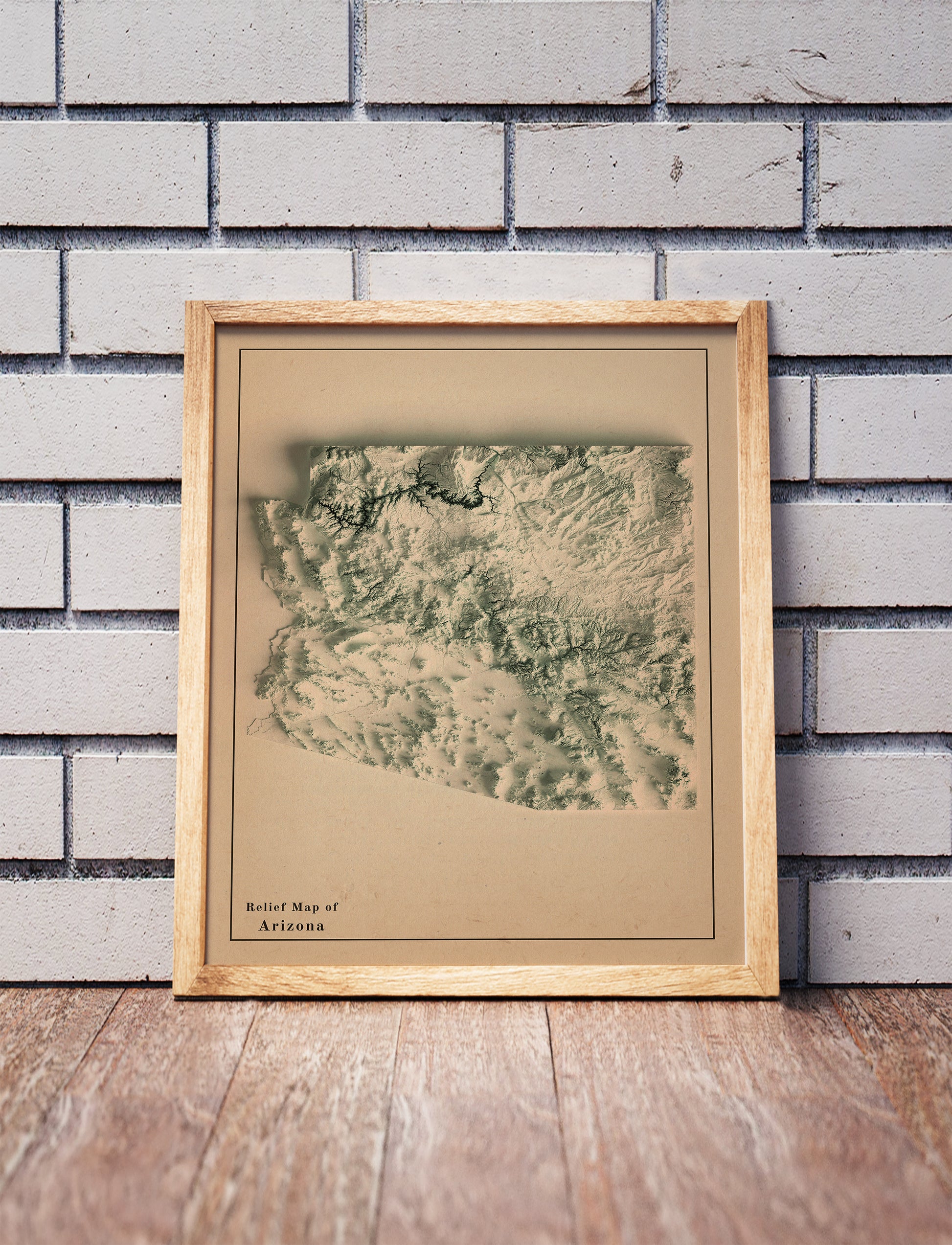 Vintage Arizona shaded relief map in a wooden frame. Realistic terrain art print for home decor, displayed against a brick wall
