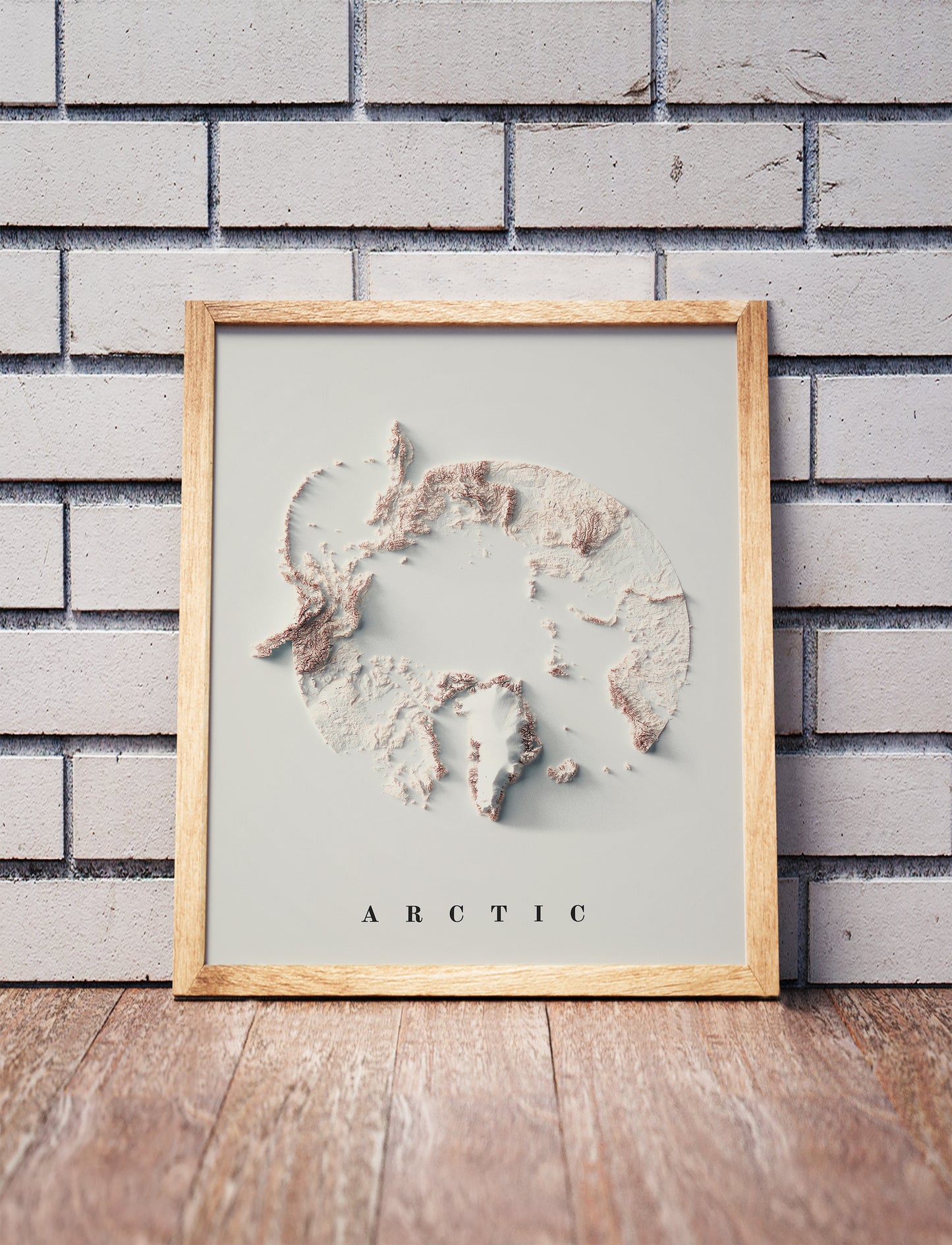 Arctic shaded relief map in a wooden frame. Realistic terrain art print for home decor, displayed against a brick wall