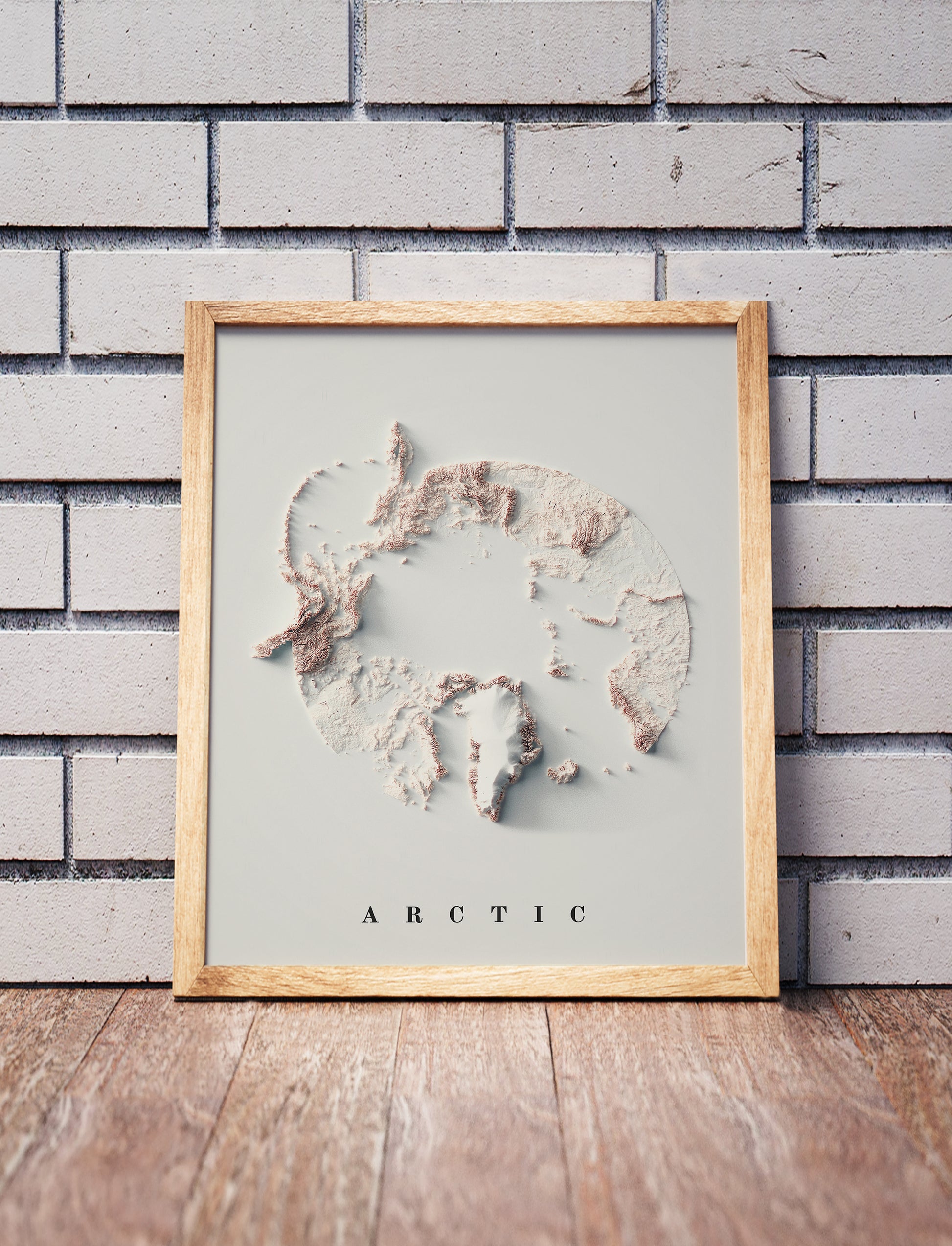Arctic shaded relief map in a wooden frame. Realistic terrain art print for home decor, displayed against a brick wall