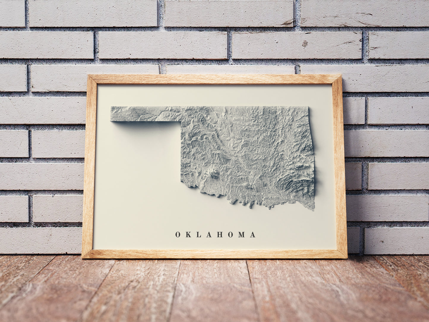 Oklahoma shaded relief map in a wooden frame. Realistic terrain art print for home decor, displayed against a brick wall