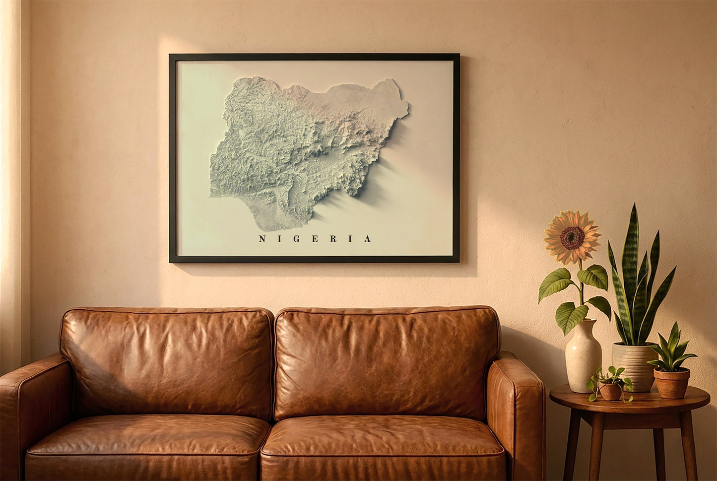 Nigeria relief map in a black frame above a brown leather sofa. Boho living room with warm sunlight, sunflower, and indoor plants on a wooden side table