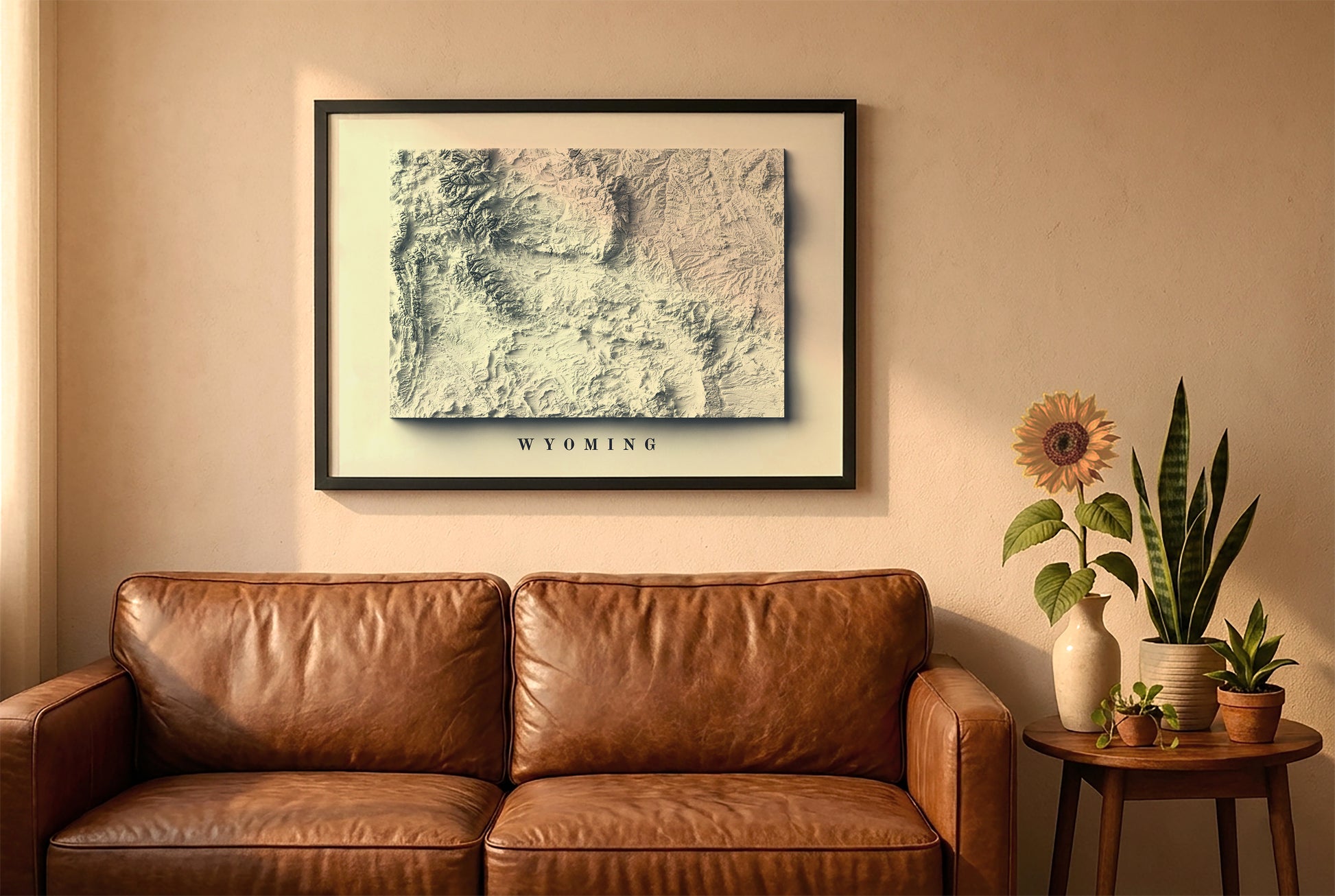 Wyoming relief map in a black frame above a brown leather sofa. Boho living room with warm sunlight, sunflower, and indoor plants on a wooden side table