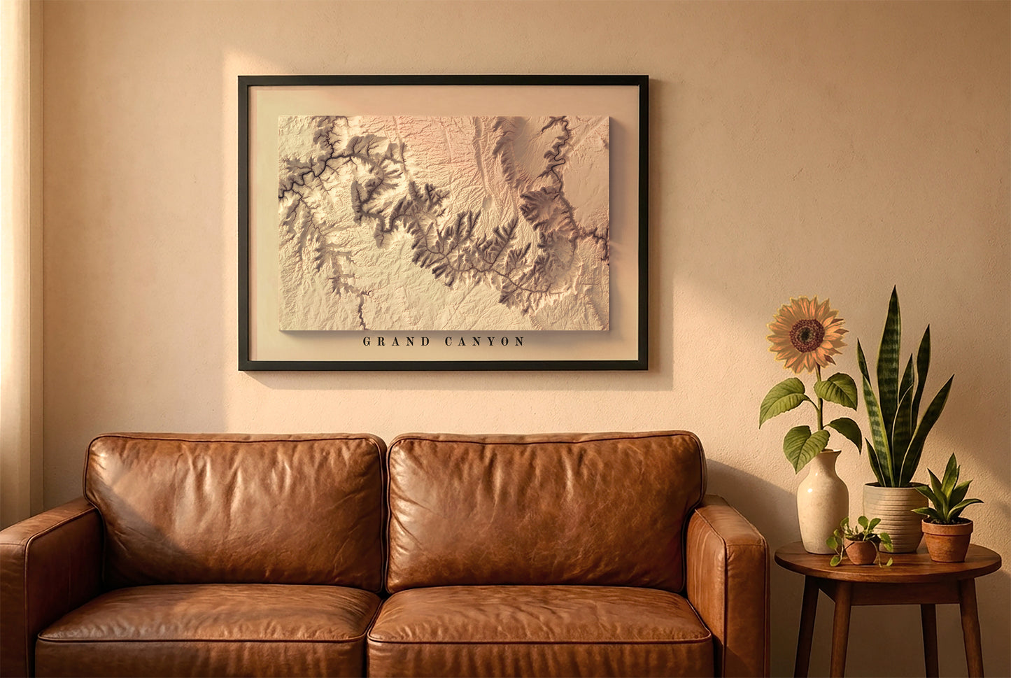 Grand Canyon relief map in a black frame above a brown leather sofa. Boho living room with warm sunlight, sunflower, and indoor plants on a wooden side table