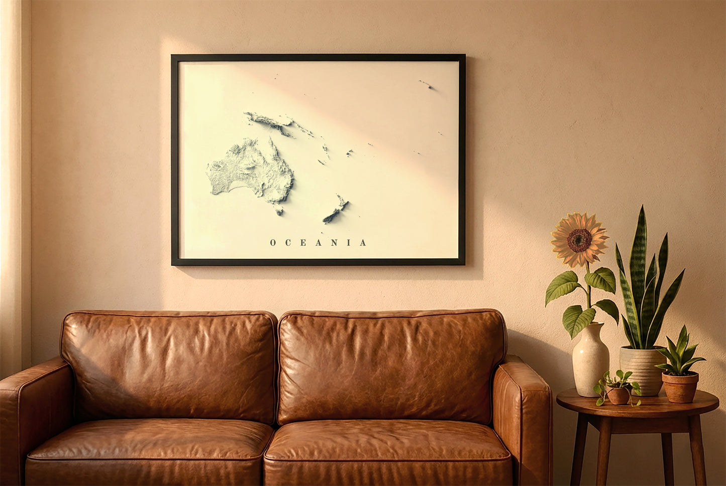 Oceania relief map in a black frame above a brown leather sofa. Boho living room with warm sunlight, sunflower, and indoor plants on a wooden side table