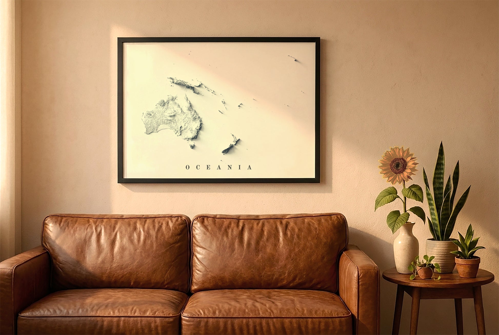 Oceania relief map in a black frame above a brown leather sofa. Boho living room with warm sunlight, sunflower, and indoor plants on a wooden side table