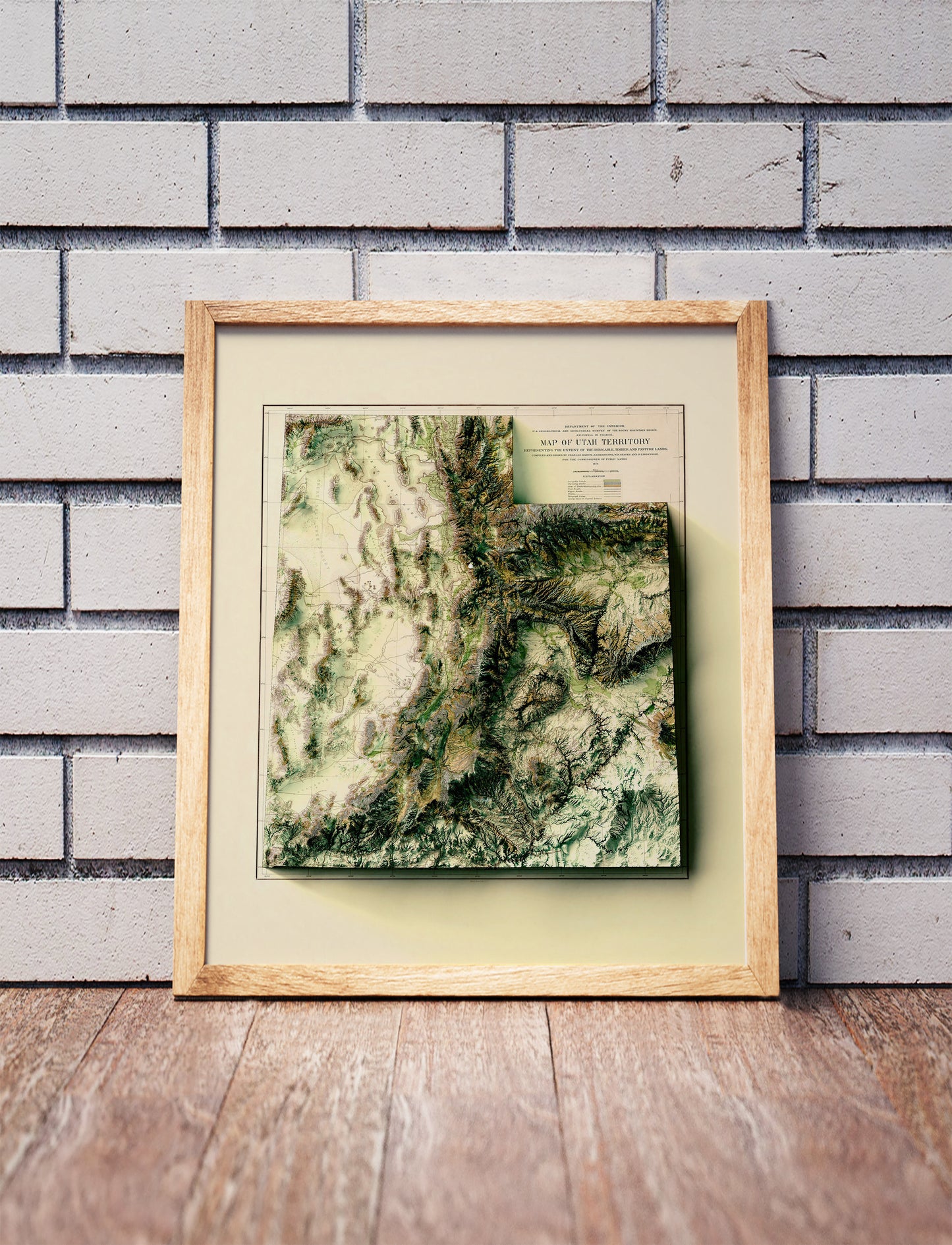 Vintage utah shaded relief map in a wooden frame. Realistic terrain art print for home decor, displayed against a brick wall