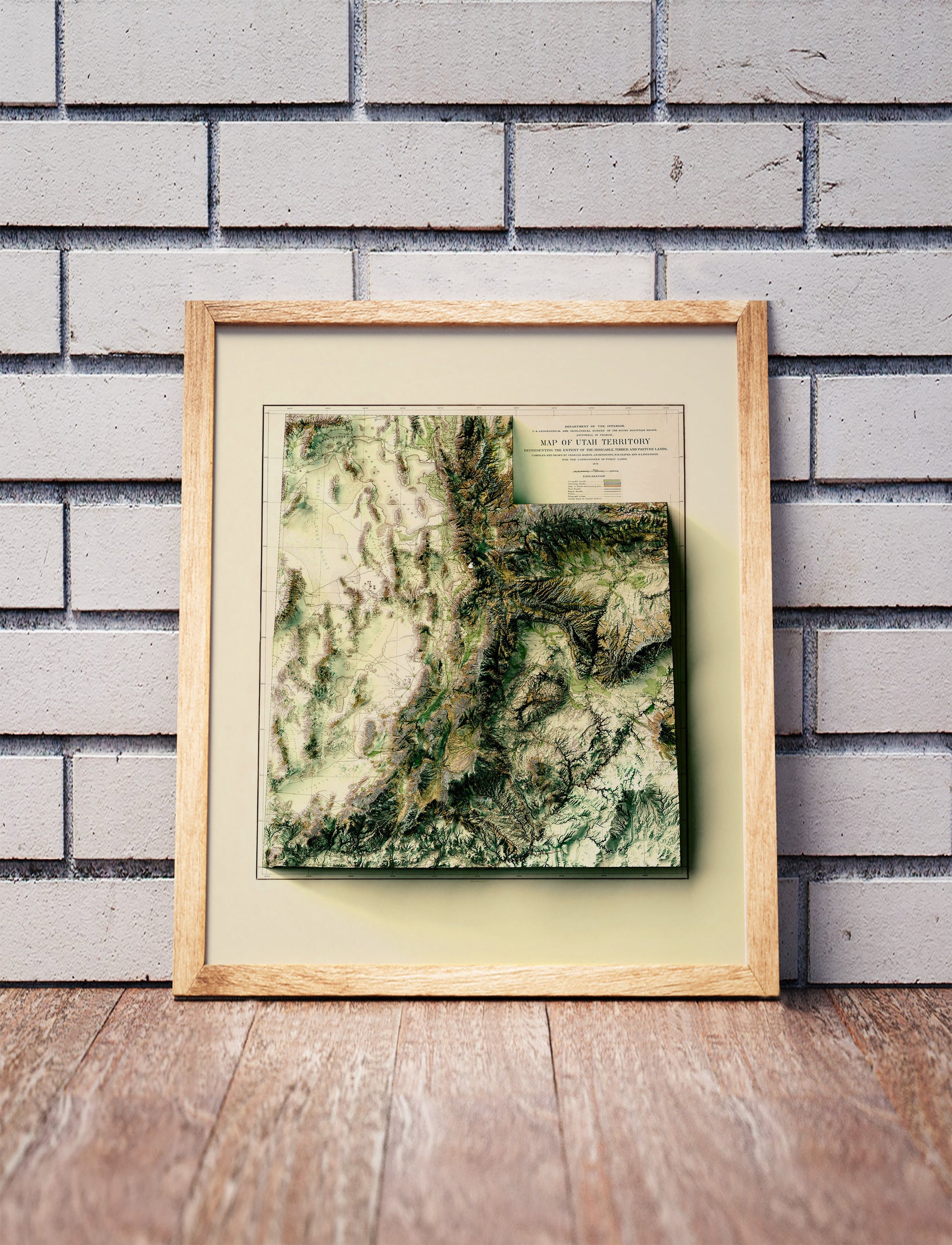 Vintage utah shaded relief map in a wooden frame. Realistic terrain art print for home decor, displayed against a brick wall