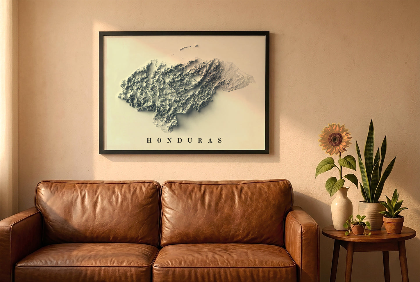Honduras relief map in a black frame above a brown leather sofa. Boho living room with warm sunlight, sunflower, and indoor plants on a wooden side table