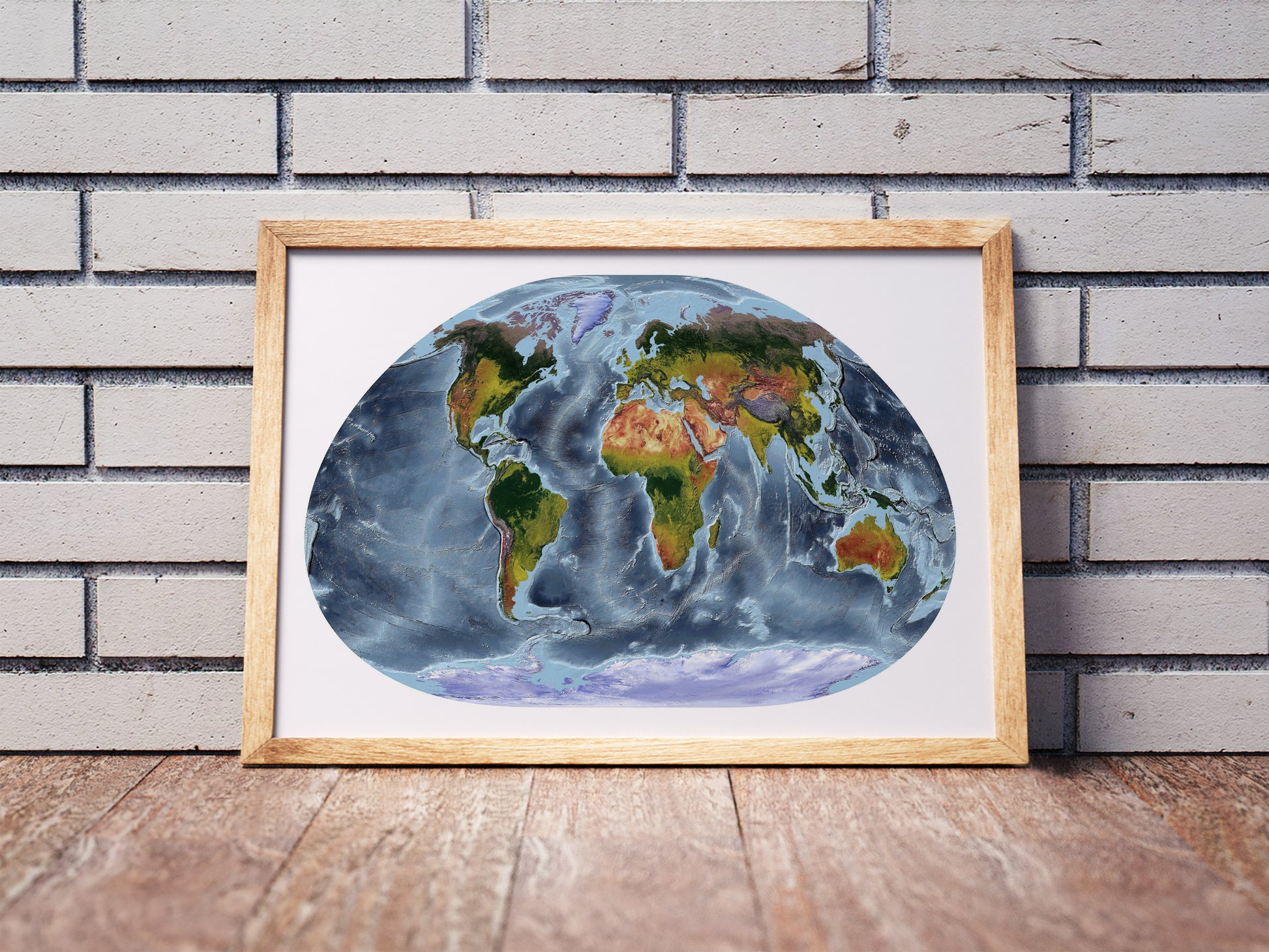 Loximuthal projection shaded relief world map in a wooden frame. Realistic terrain art print for home decor, displayed against a brick wall