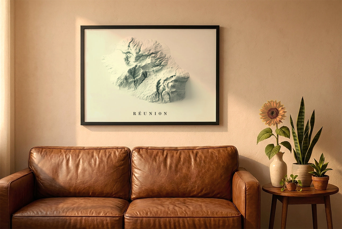 Reunion, France, relief map in a black frame above a brown leather sofa. Boho living room with warm sunlight, sunflower, and indoor plants on a wooden side table