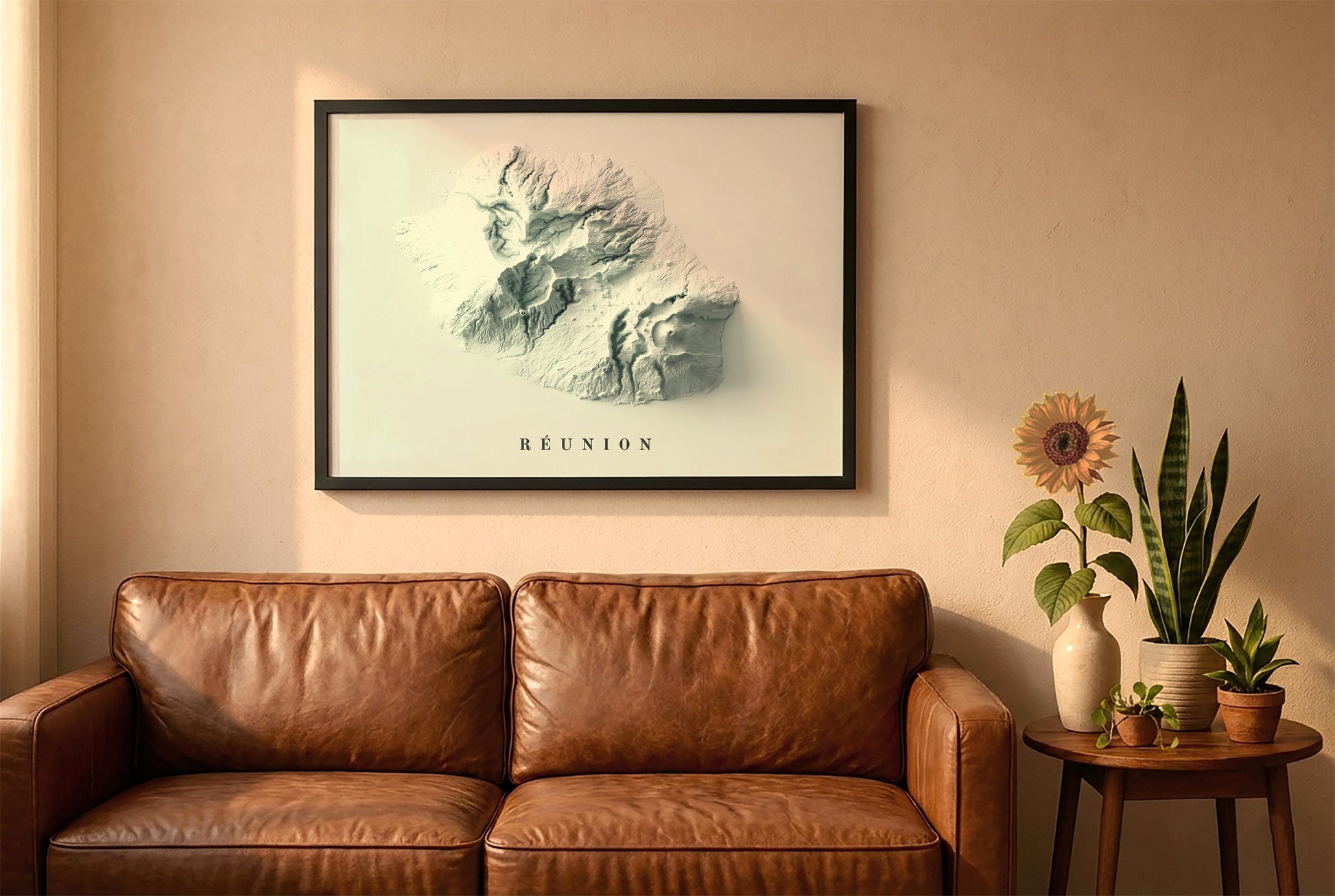 Reunion, France, relief map in a black frame above a brown leather sofa. Boho living room with warm sunlight, sunflower, and indoor plants on a wooden side table