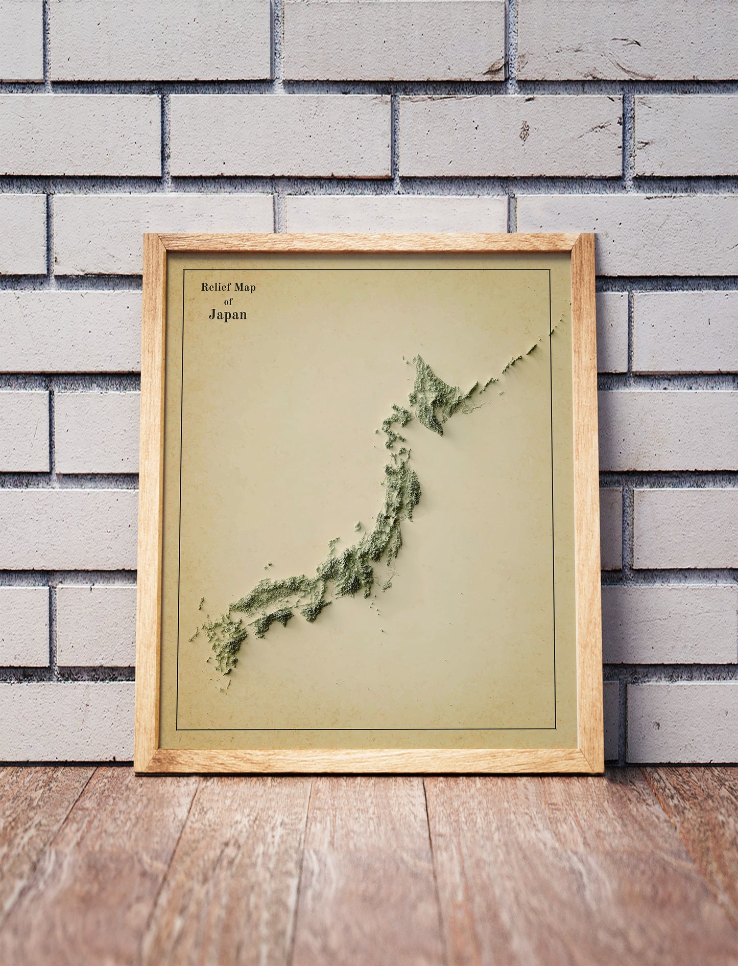 Vintage Japan shaded relief map in a wooden frame. Realistic terrain art print for home decor, displayed against a brick wall