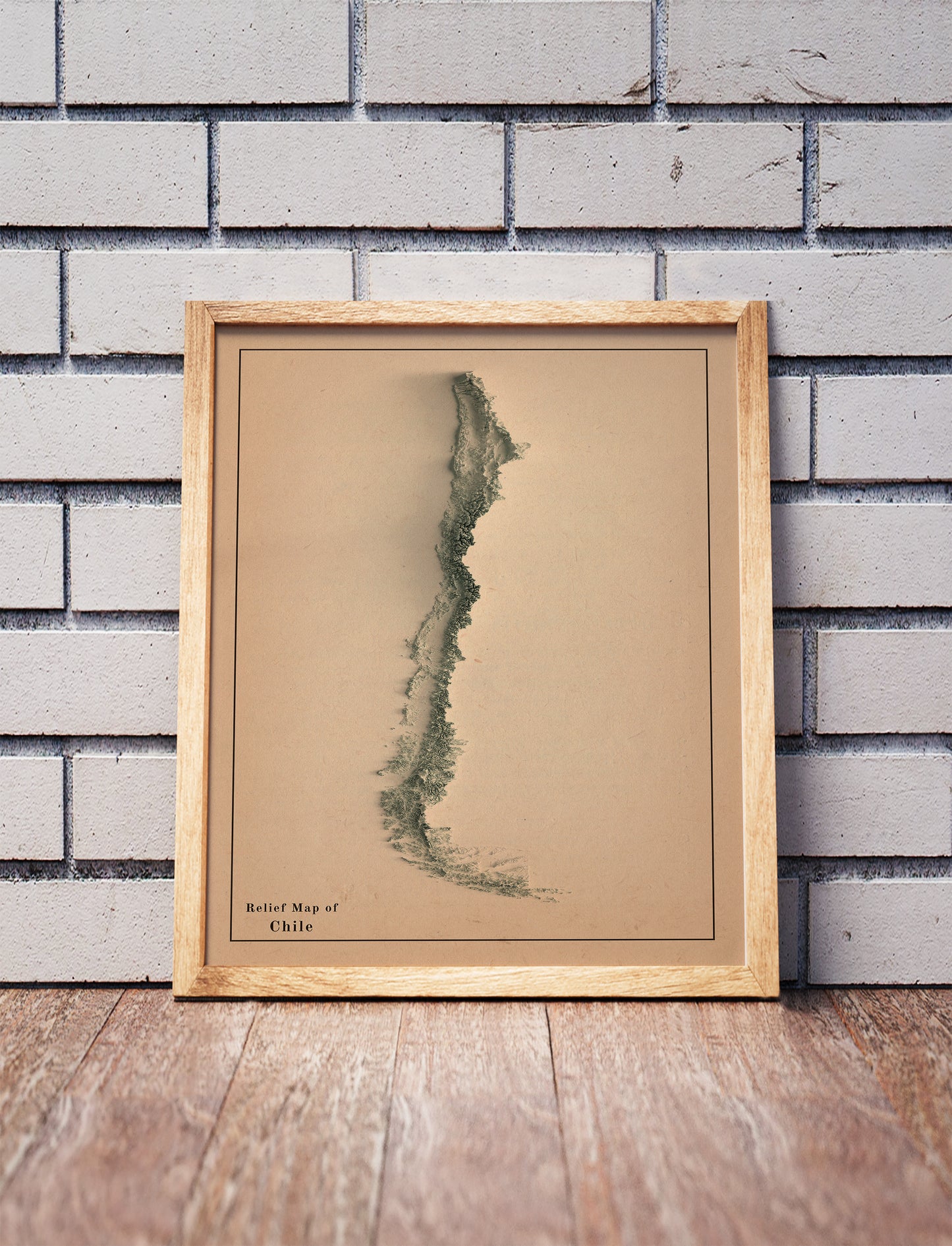 Vintage Chile shaded relief map in a wooden frame. Realistic terrain art print for home decor, displayed against a brick wall