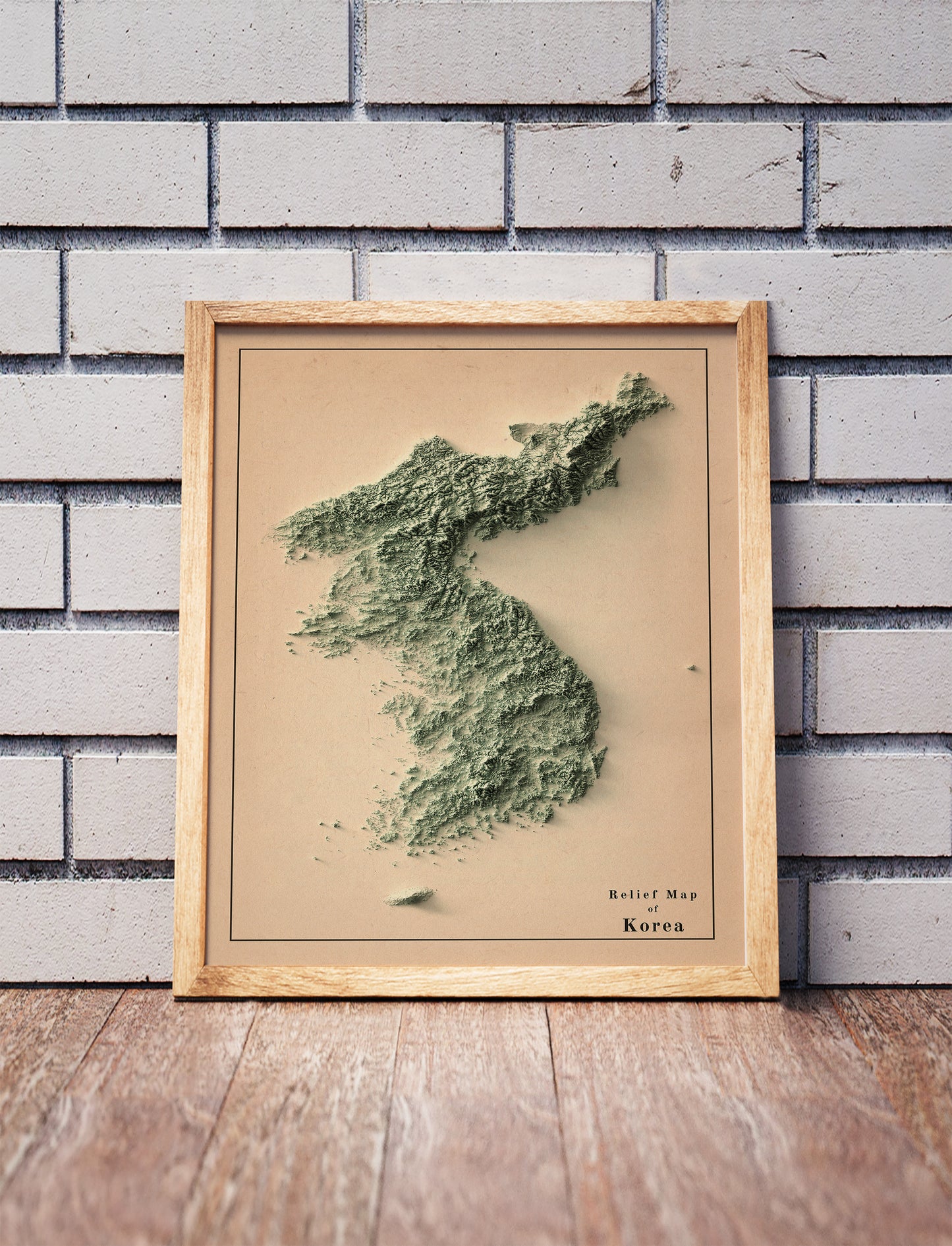 Vintage North and South Koreas shaded relief map in a wooden frame. Realistic terrain art print for home decor, displayed against a brick wall