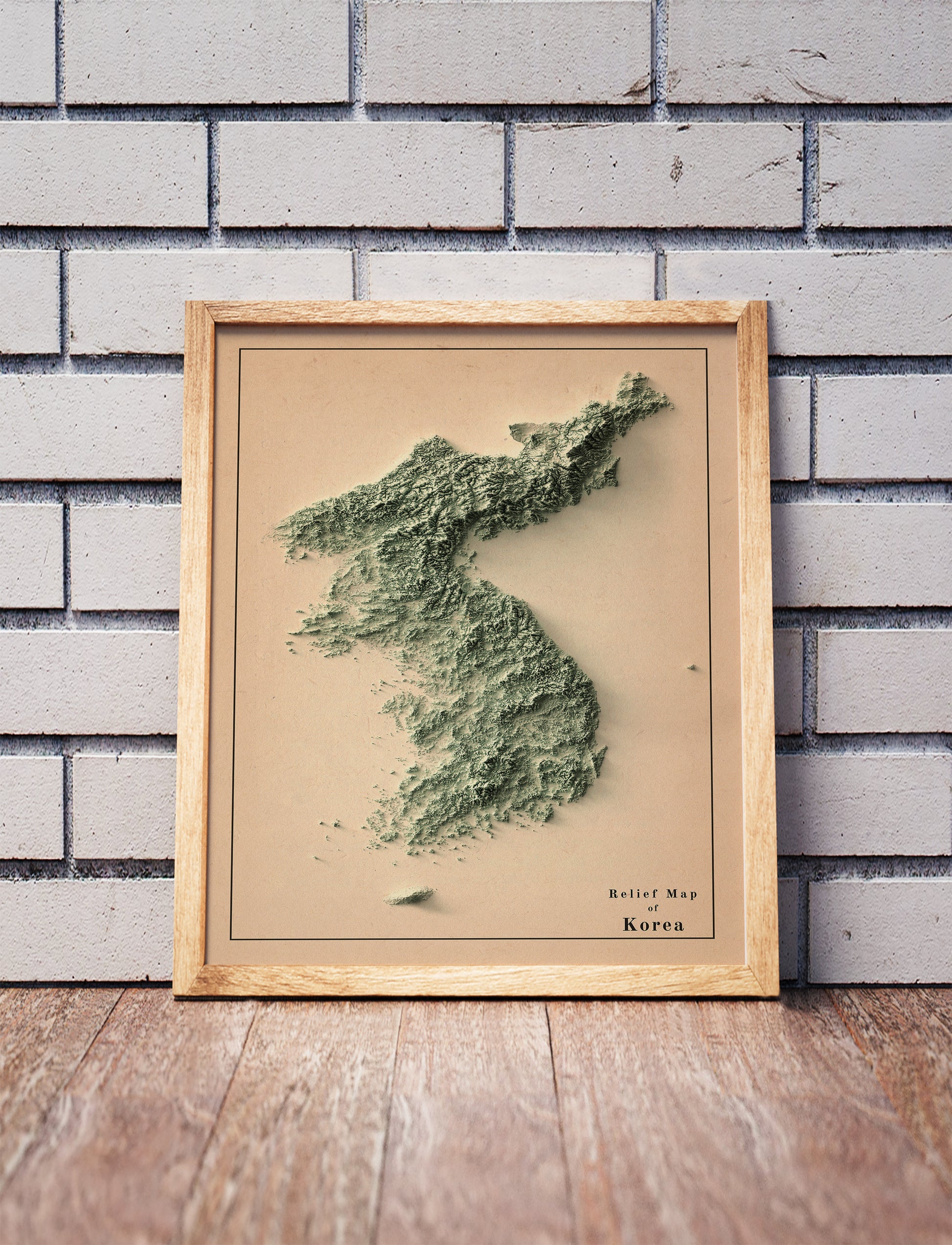 Vintage North and South Koreas shaded relief map in a wooden frame. Realistic terrain art print for home decor, displayed against a brick wall