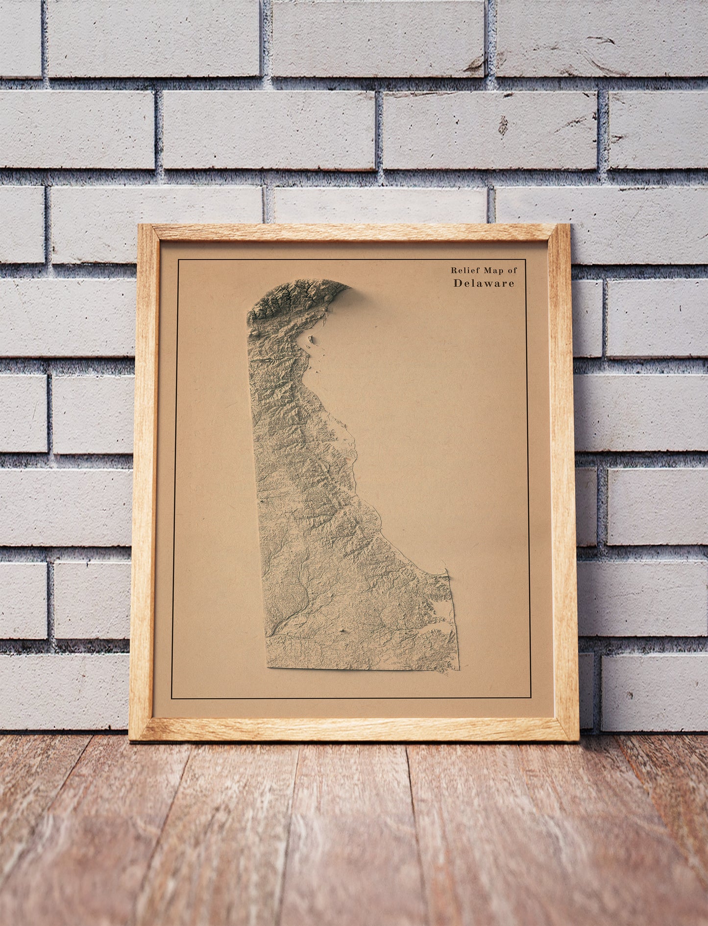 Vintage Delaware shaded relief map in a wooden frame. Realistic terrain art print for home decor, displayed against a brick wall