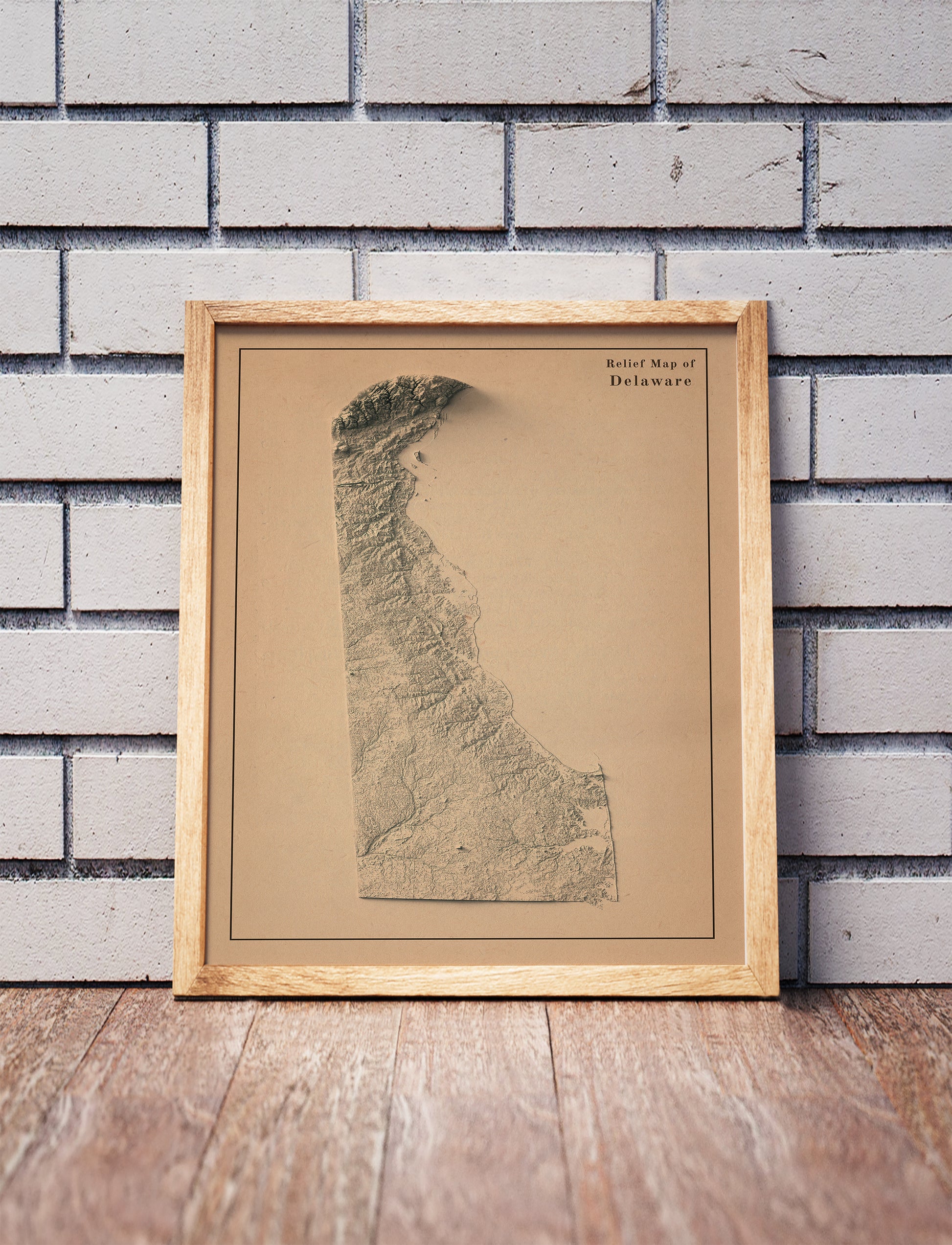 Vintage Delaware shaded relief map in a wooden frame. Realistic terrain art print for home decor, displayed against a brick wall