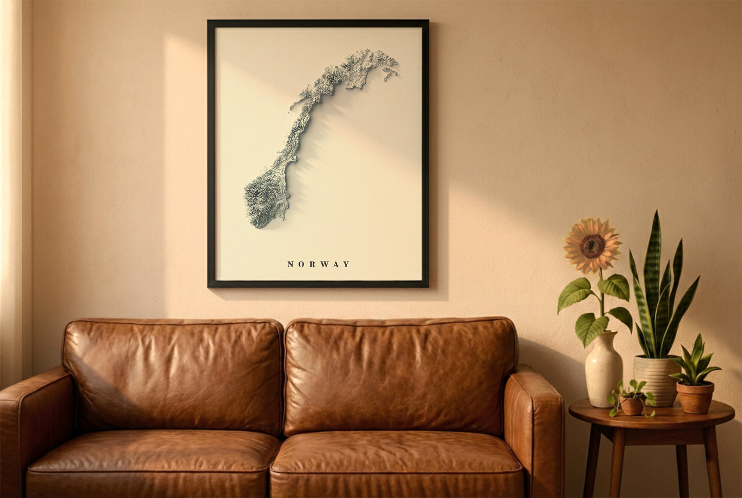 Norway relief map in a black frame above a brown leather sofa. Boho living room with warm sunlight, sunflower, and indoor plants on a wooden side table