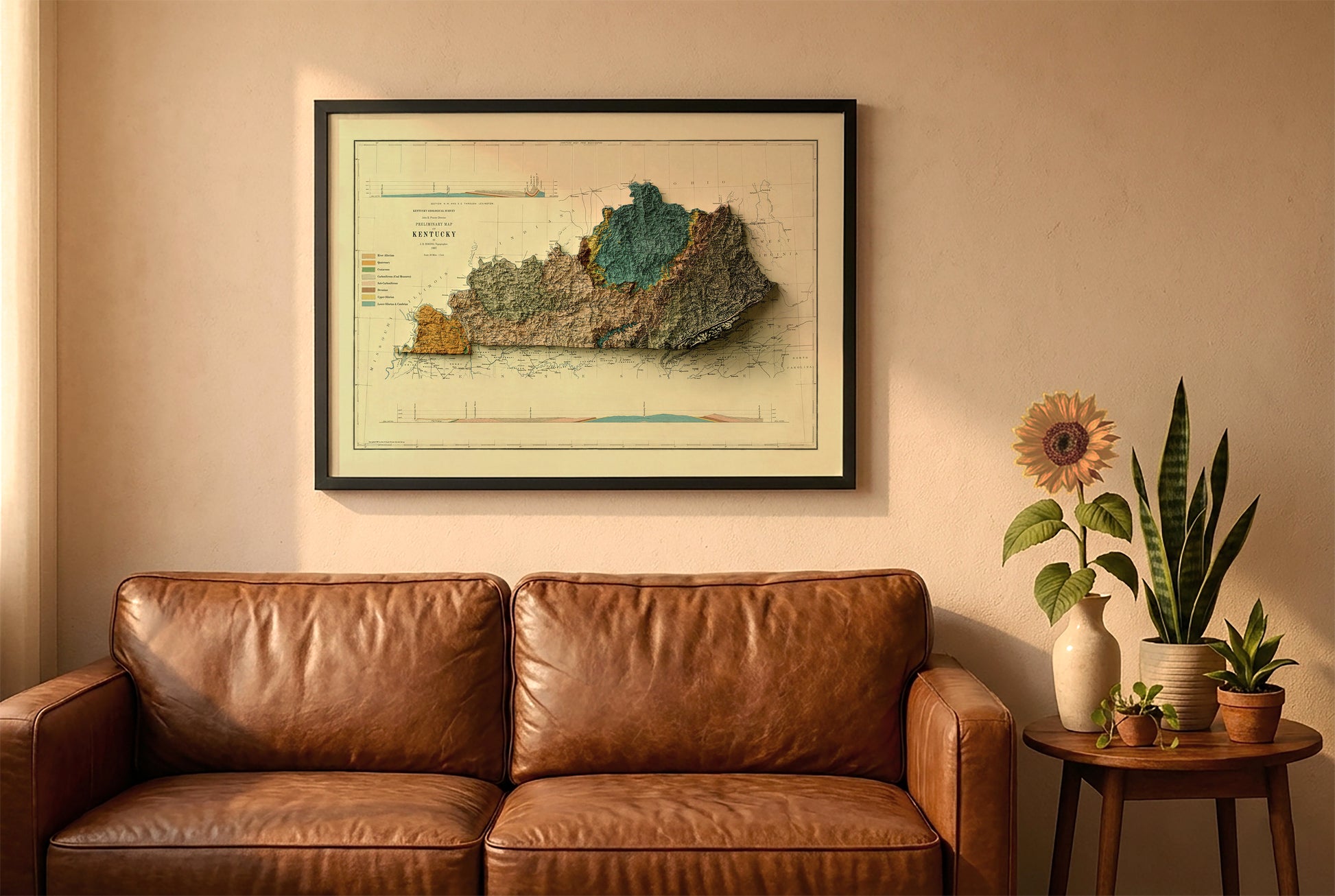 Kentucky vintage relief map in a black frame above a brown leather sofa. Boho living room with warm sunlight, sunflower, and indoor plants on a wooden side table