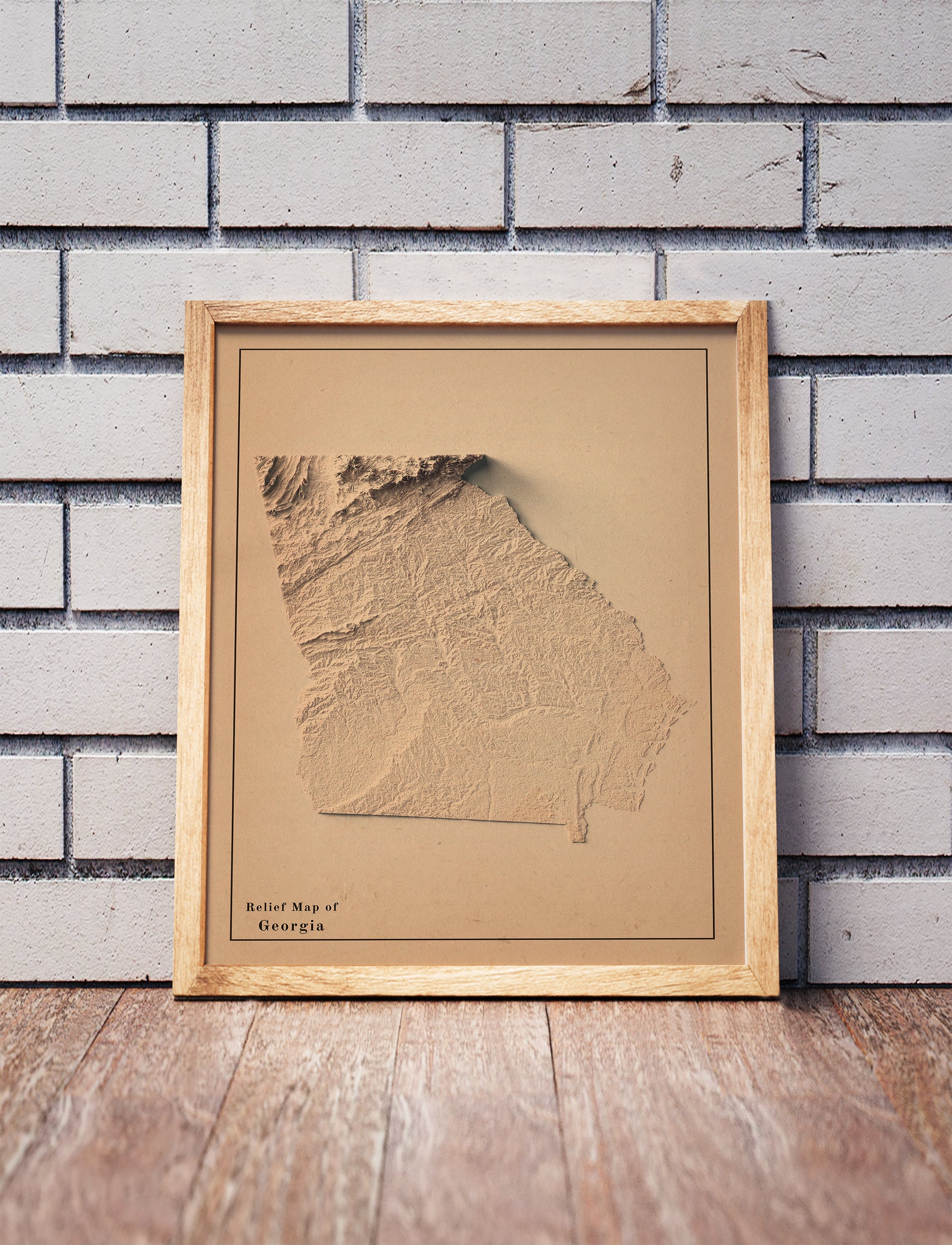 Vintage Georgia shaded relief map in a wooden frame. Realistic terrain art print for home decor, displayed against a brick wall