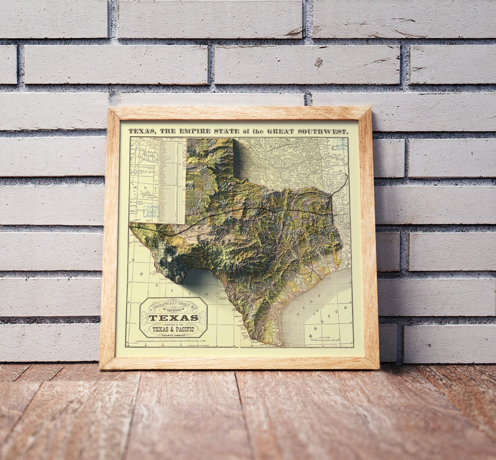 Vintage Texas shaded relief map in a wooden frame. Realistic terrain art print for home decor, displayed against a brick wall
